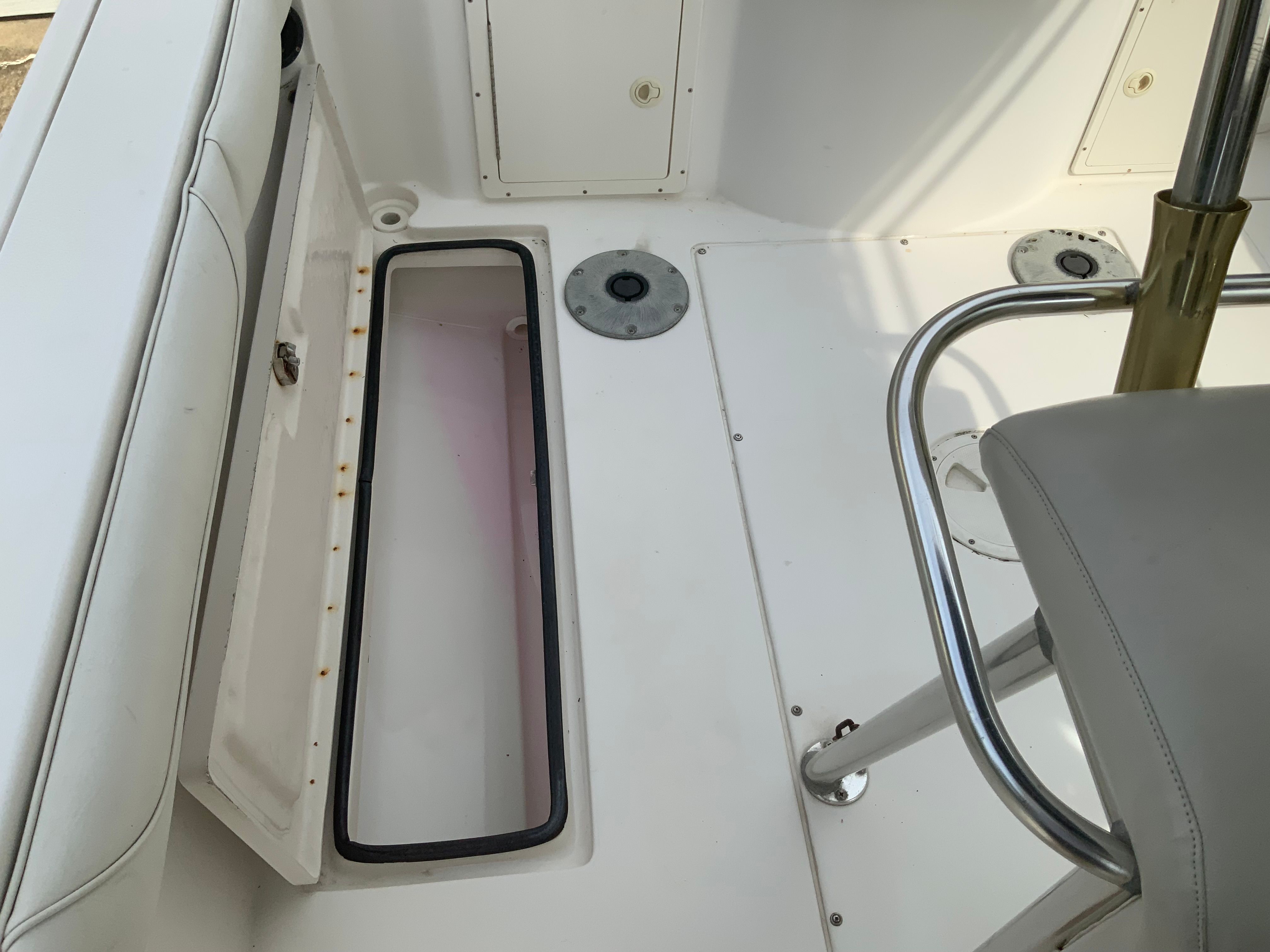 The image shows a boat cockpit with white seating and an open storage compartment.