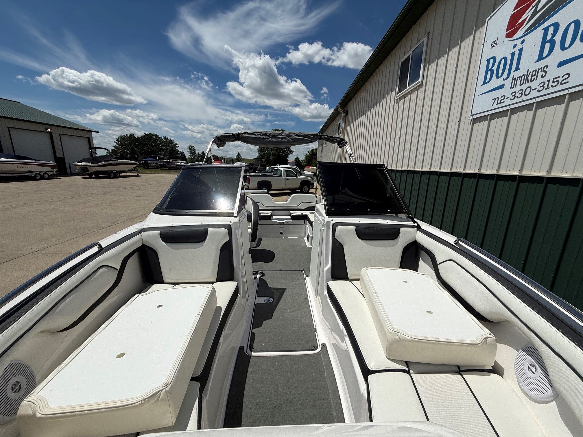 A Yamaha SX210 boat is parked on a lot next to a building.