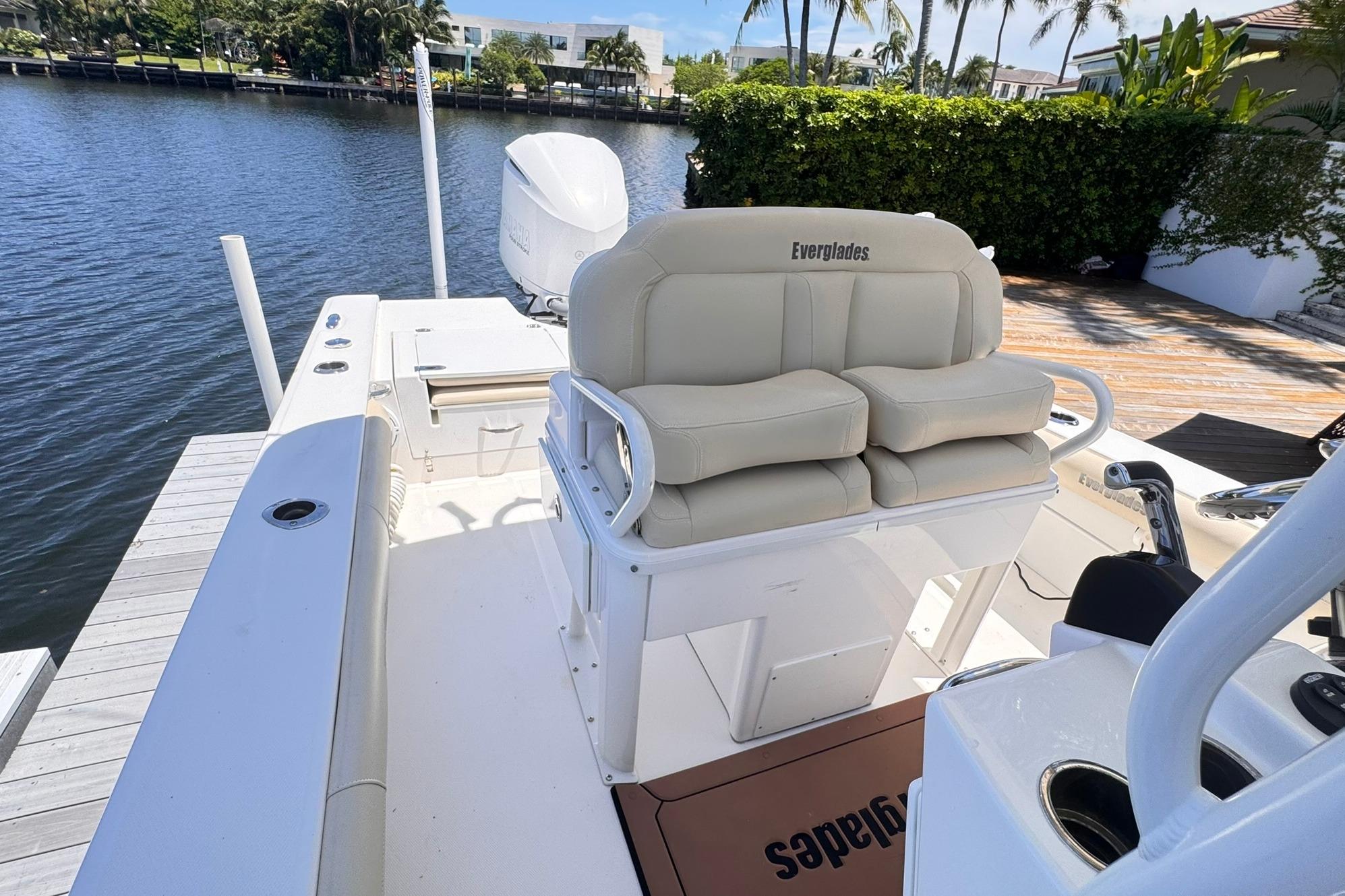 2018 Everglades 253 Center Console boat with cushioned seating, docked by a scenic waterfront.
