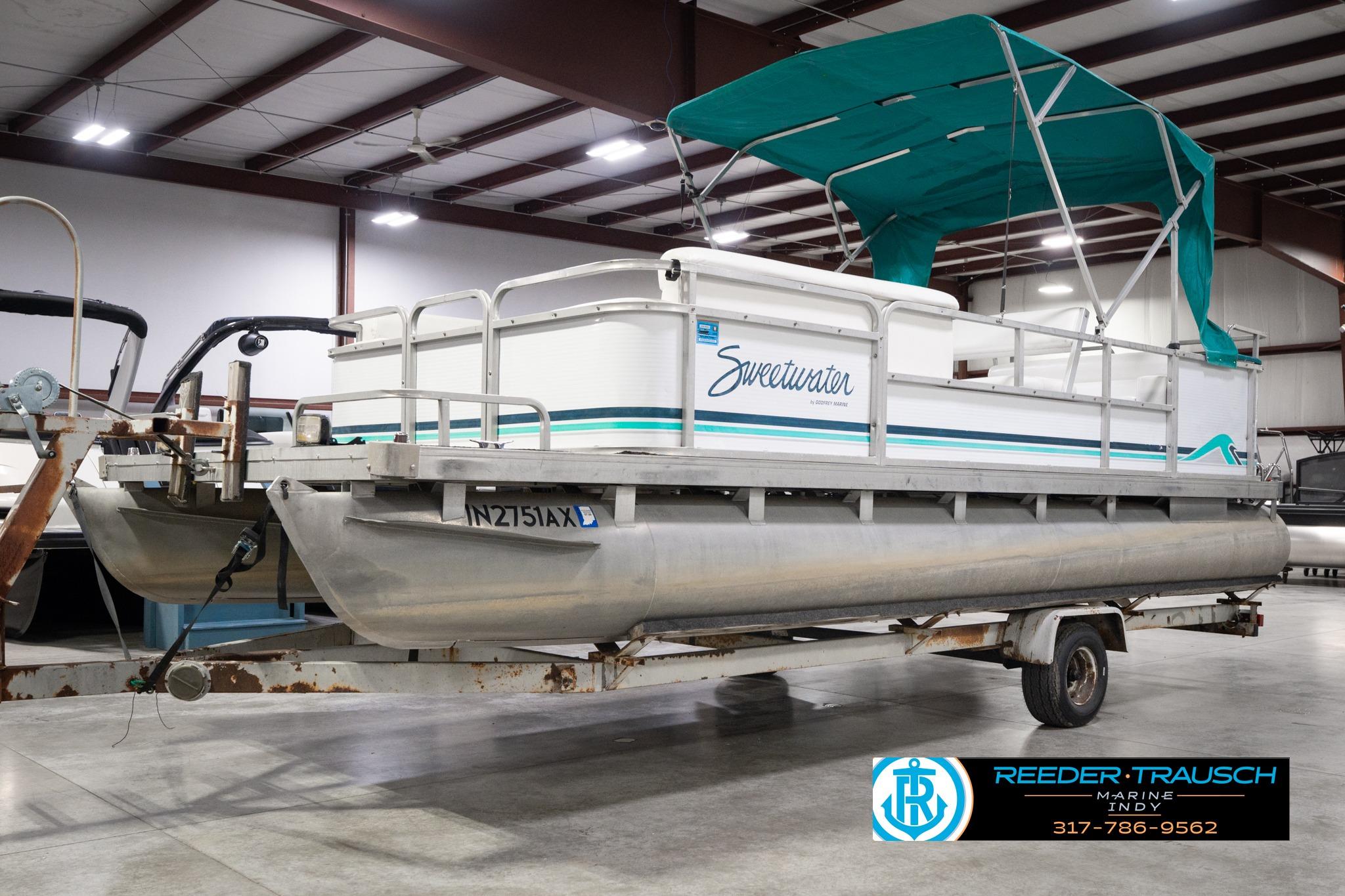 1992 Godfrey Sweetwater pontoon boat with teal canopy in indoor storage.