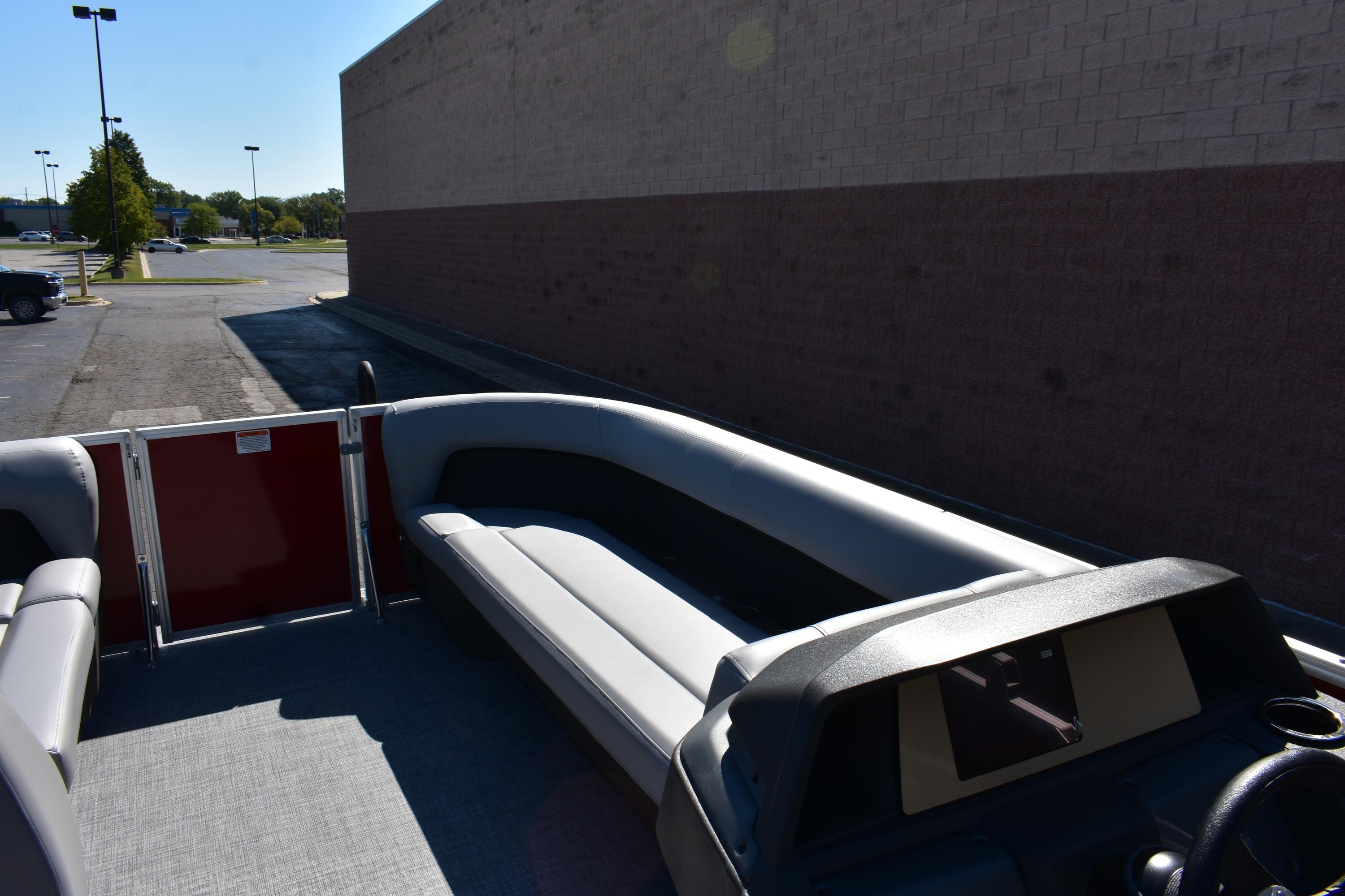 2026 Sun Tracker Party Barge 18 DLX interior with seating and console, parked outdoors.