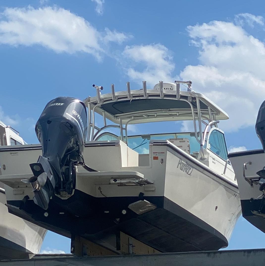 2015 Parker 2510 XLD boat with outboard motor, docked under a blue sky.
