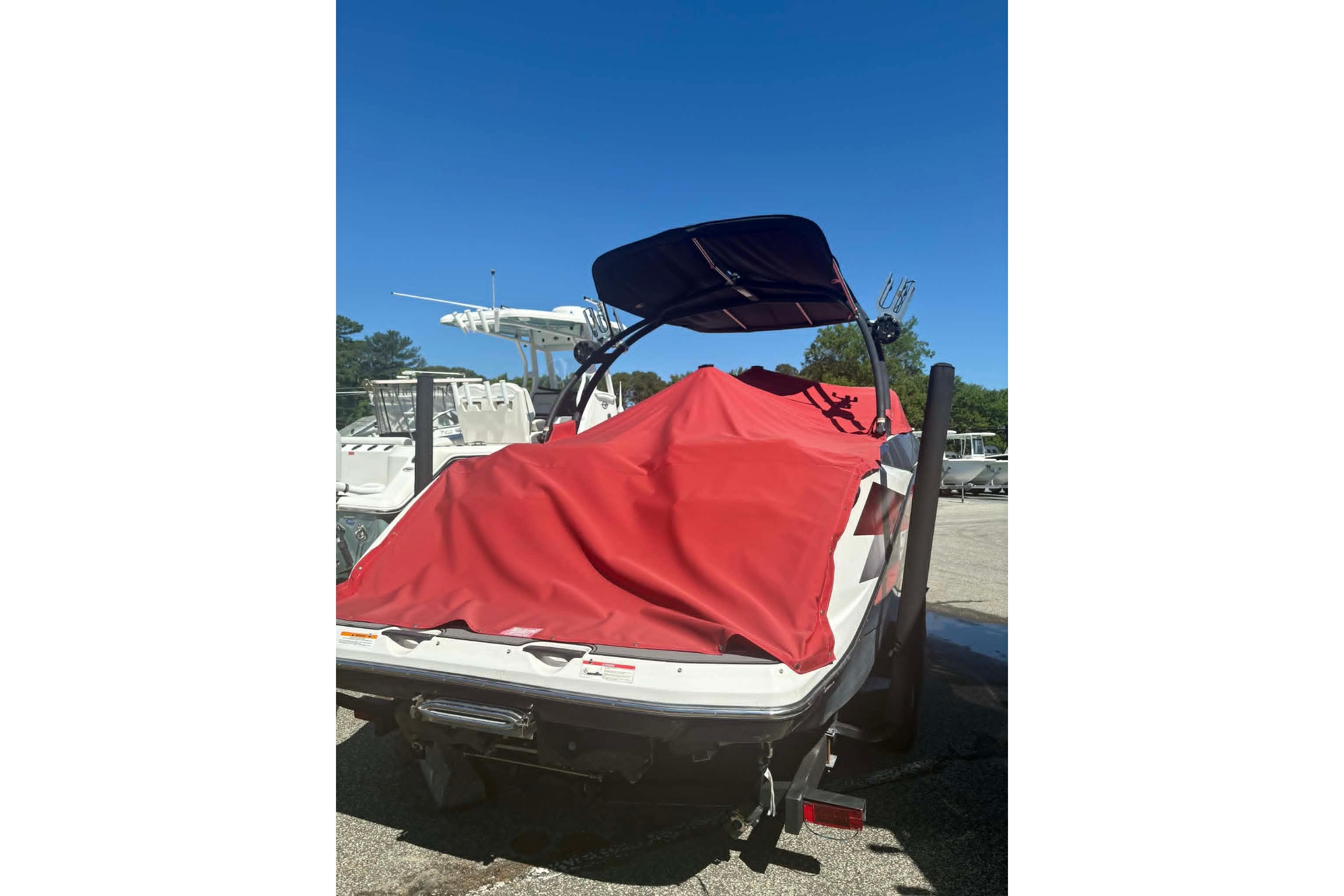 2016 Scarab 255 H.O. Impulse boat with red cover, parked outdoors.