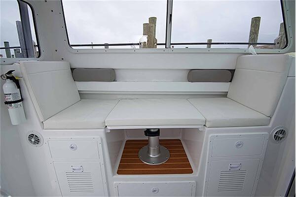 2026 Steiger Craft 28 Fisherman interior seating with storage and fire extinguisher.