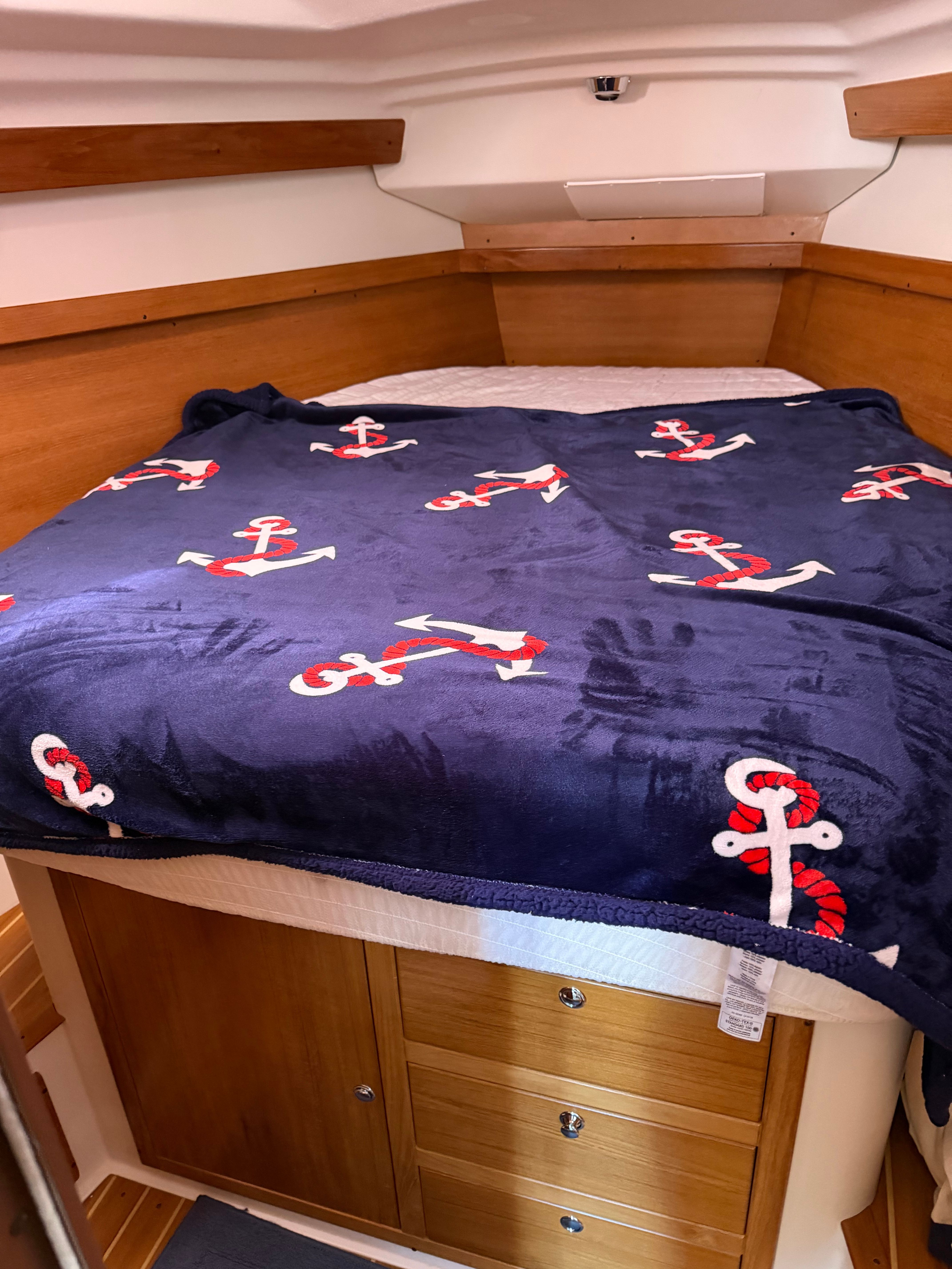 Cabin with blue anchor-themed bedding in a 2004 Catalina 350.