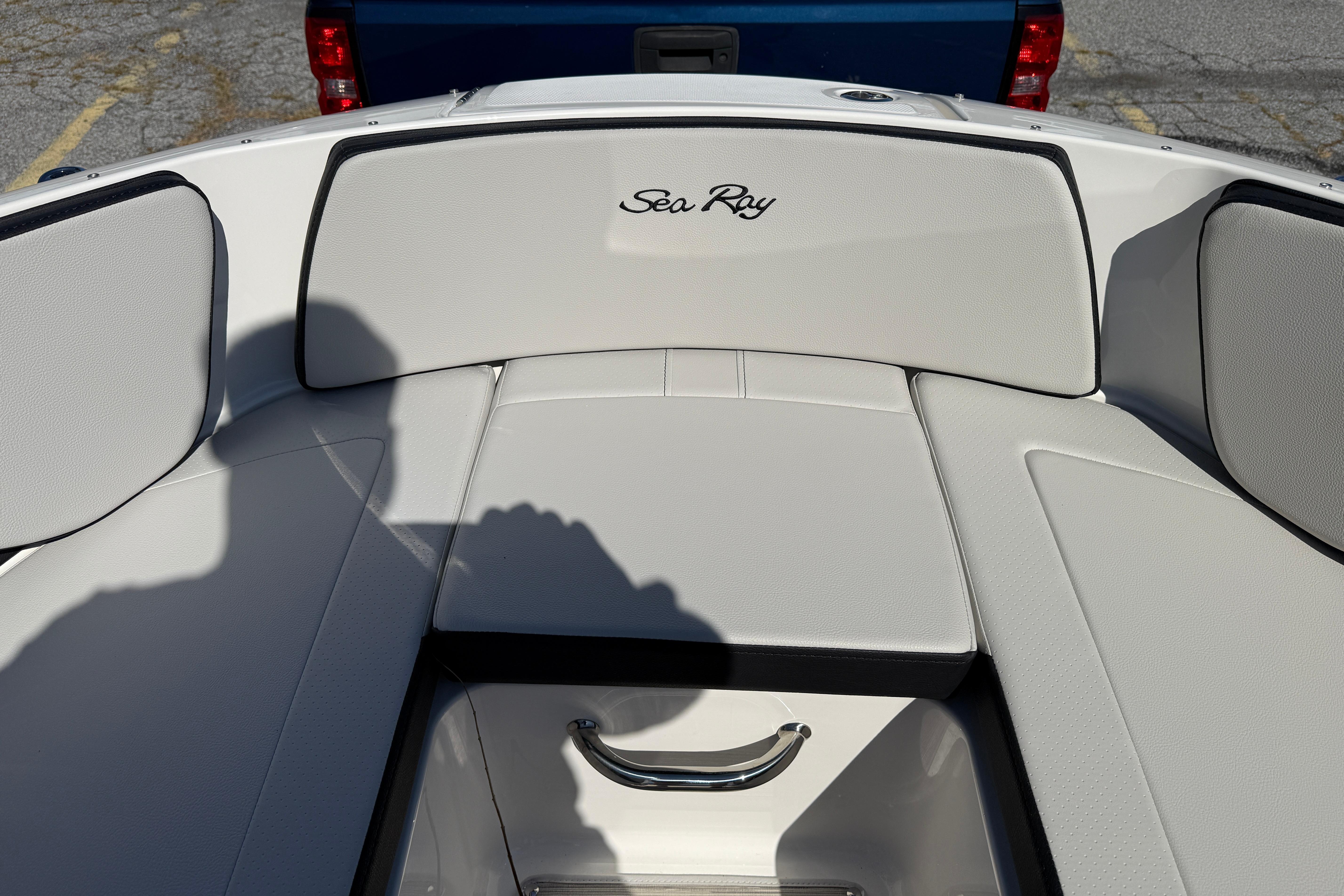 2026 Sea Ray SPX 210 boat interior with white cushioned seating and storage compartment.