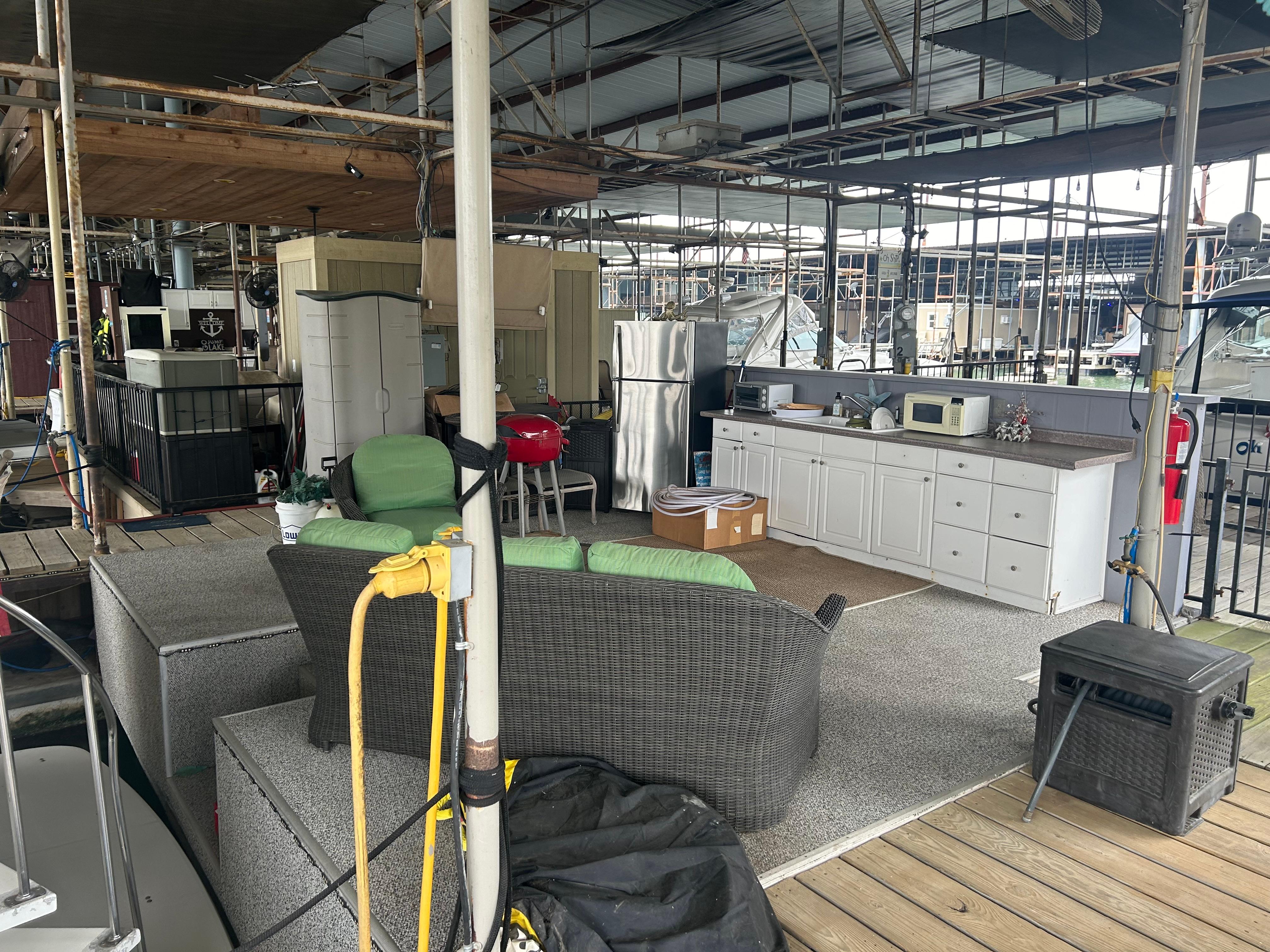 Outdoor dock setup with seating, kitchen area, and appliances near a 1996 Carver 440 Aft Cabin Motor Yacht.