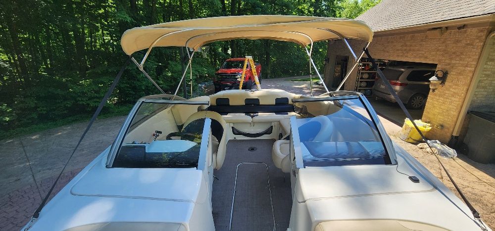 A 2007 Sea-Doo Sport Boat 230 Challenger SE with a beige canopy, parked in a driveway.
