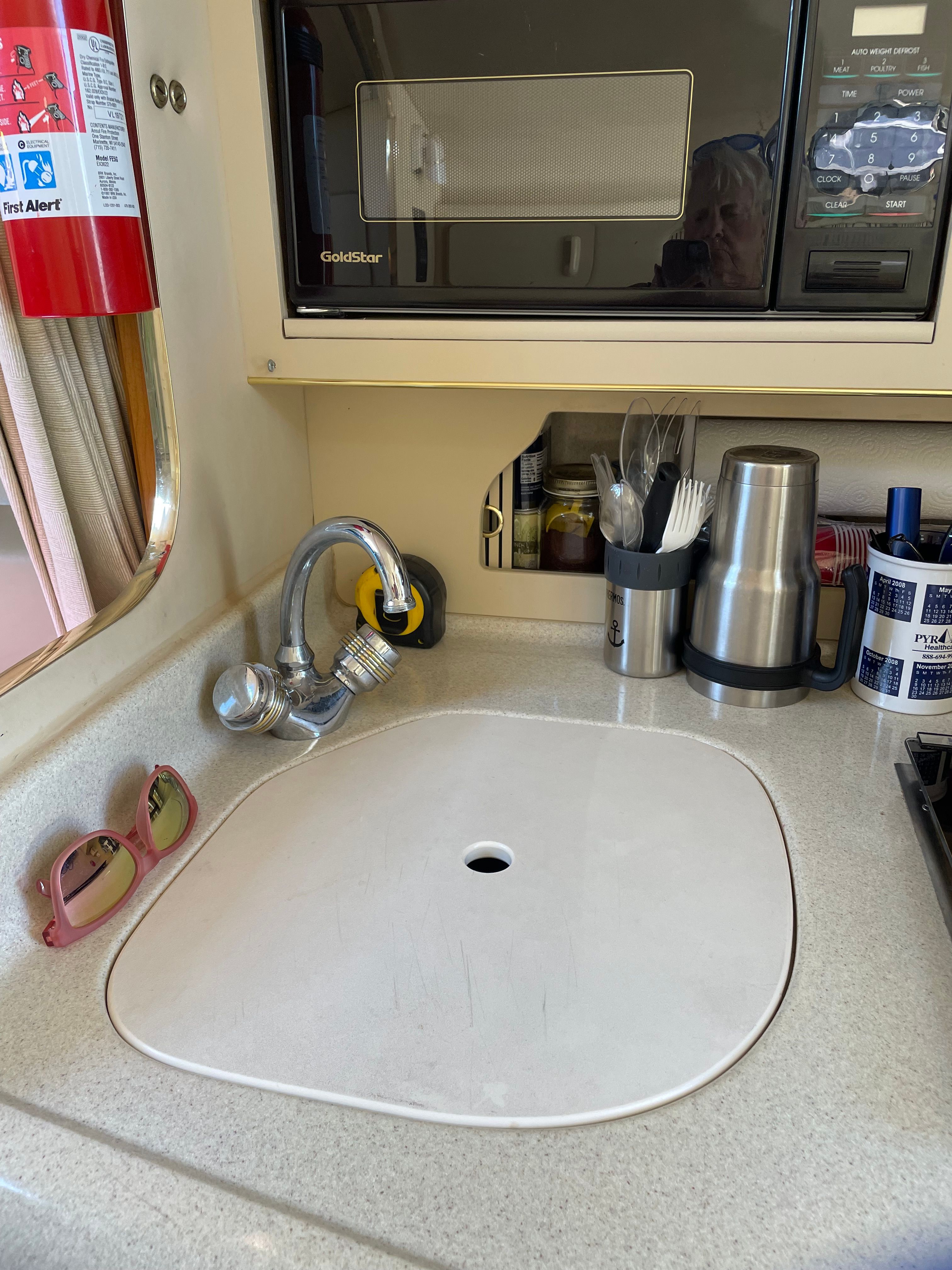 Galley area with sink, faucet, microwave, and kitchen utensils.