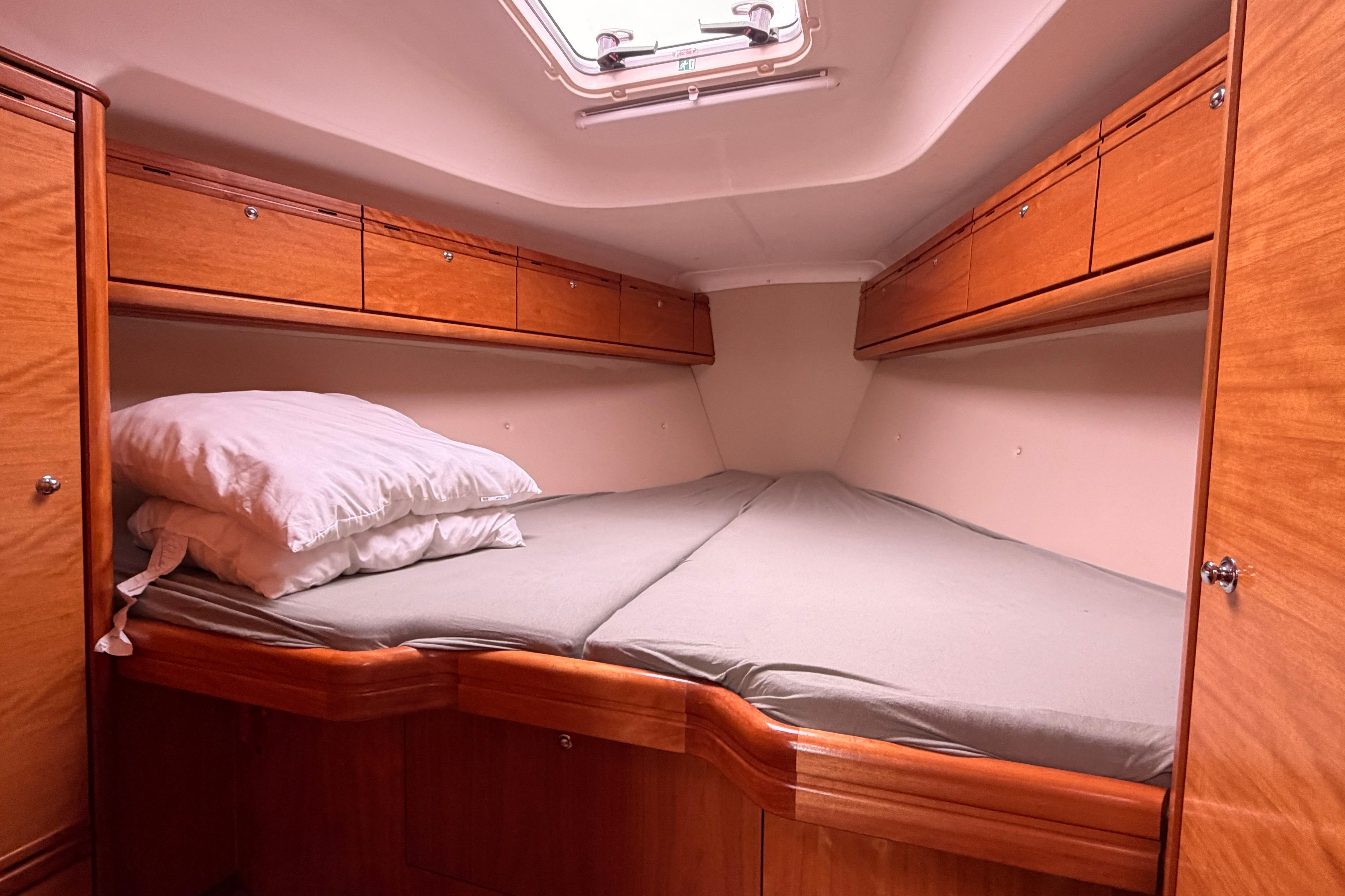 Cozy cabin interior of 2009 Bavaria 34 Cruiser yacht with wooden storage and bedding.
