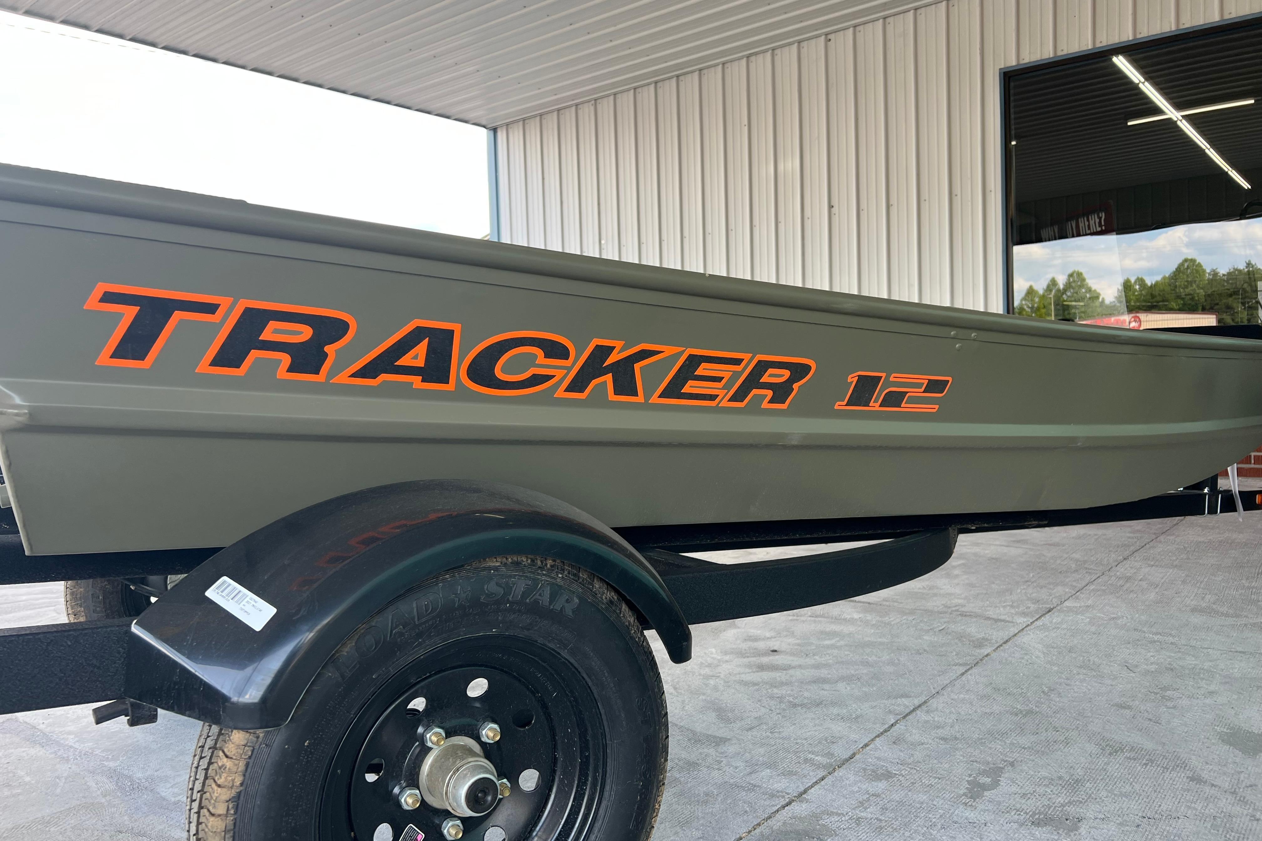 2026 Tracker Grizzly 12 Jon boat on trailer, displayed in a showroom.