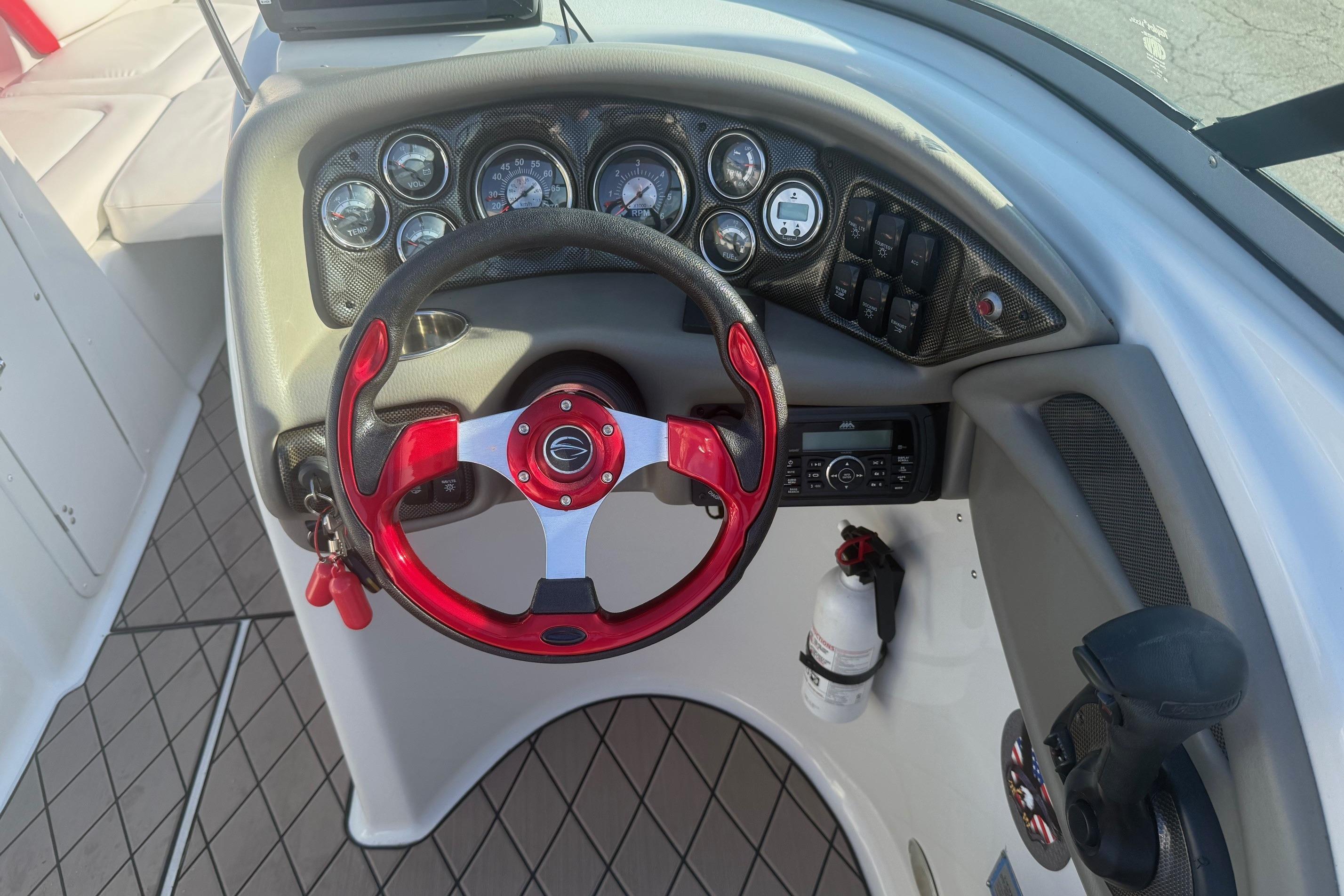 Cockpit of 2005 Crownline 270 BR boat with red steering wheel and control panel.