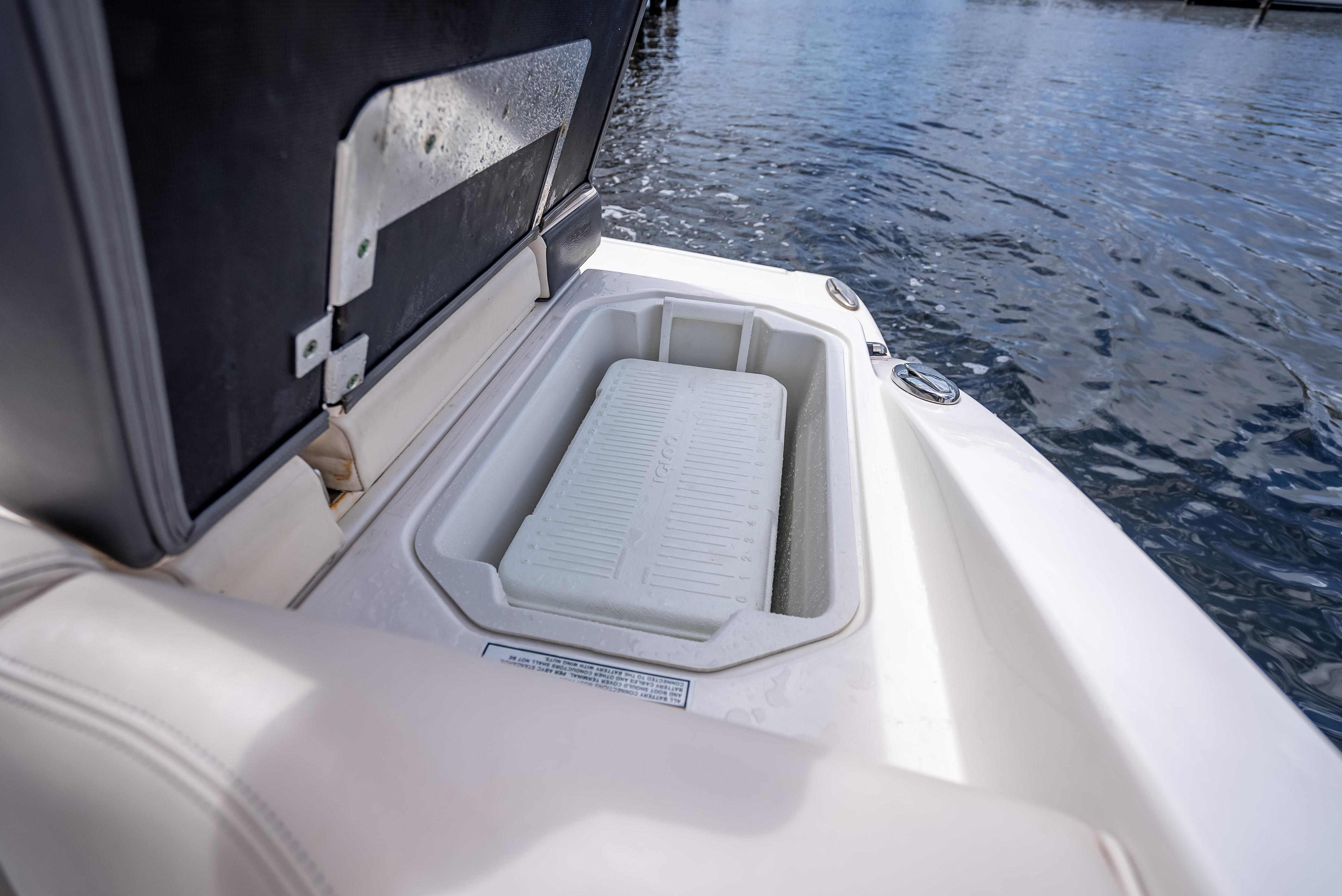 Open storage compartment on 2017 Chaparral 227 SSX boat, near water.