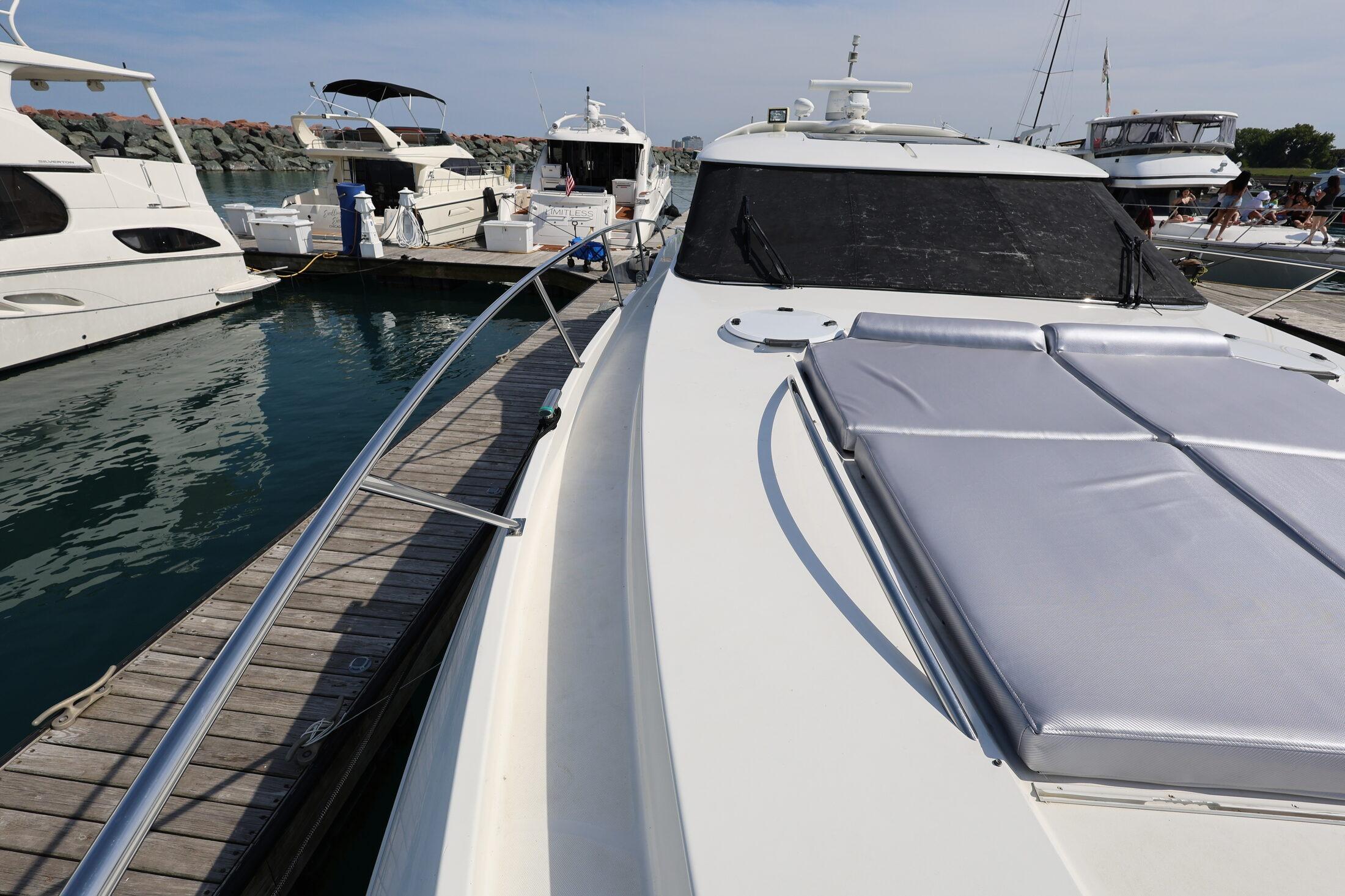 1999 Neptunus 54 Express yacht docked at marina, featuring sleek design and sunbathing area.
