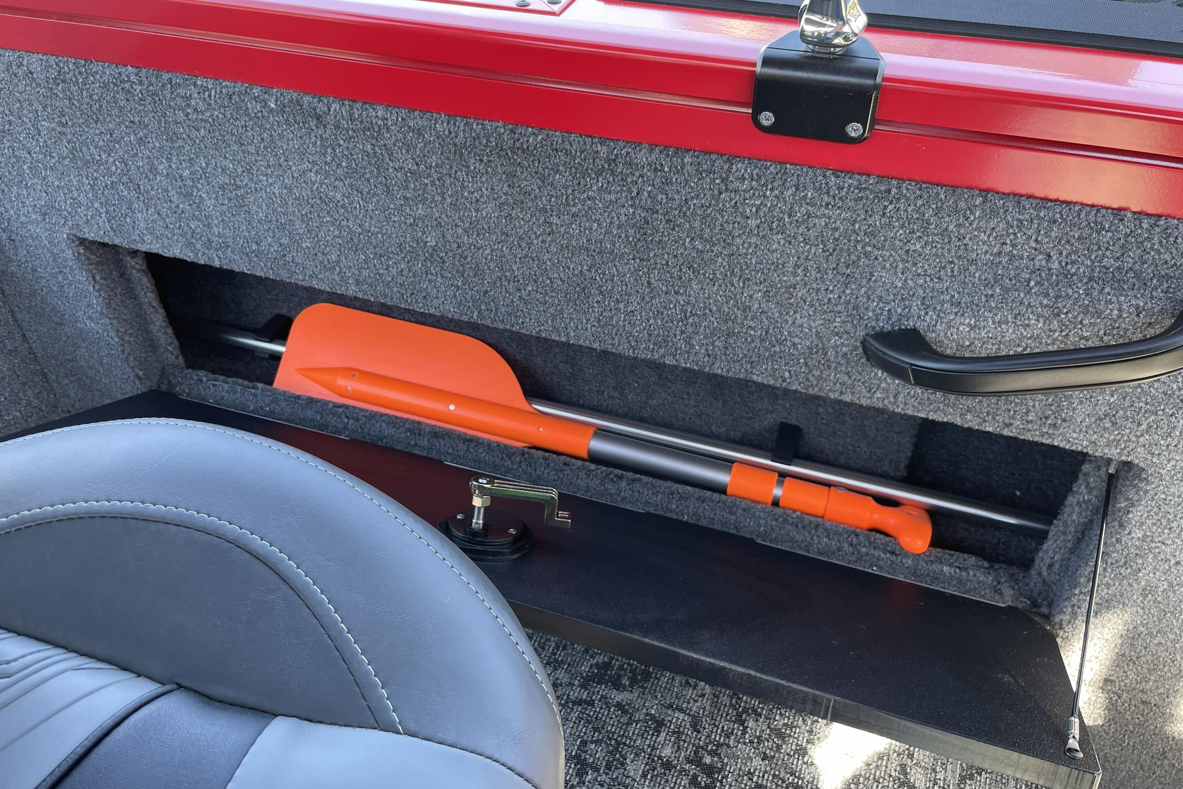 Storage compartment in 2026 Tracker Targa V-18 WT boat with orange paddle.