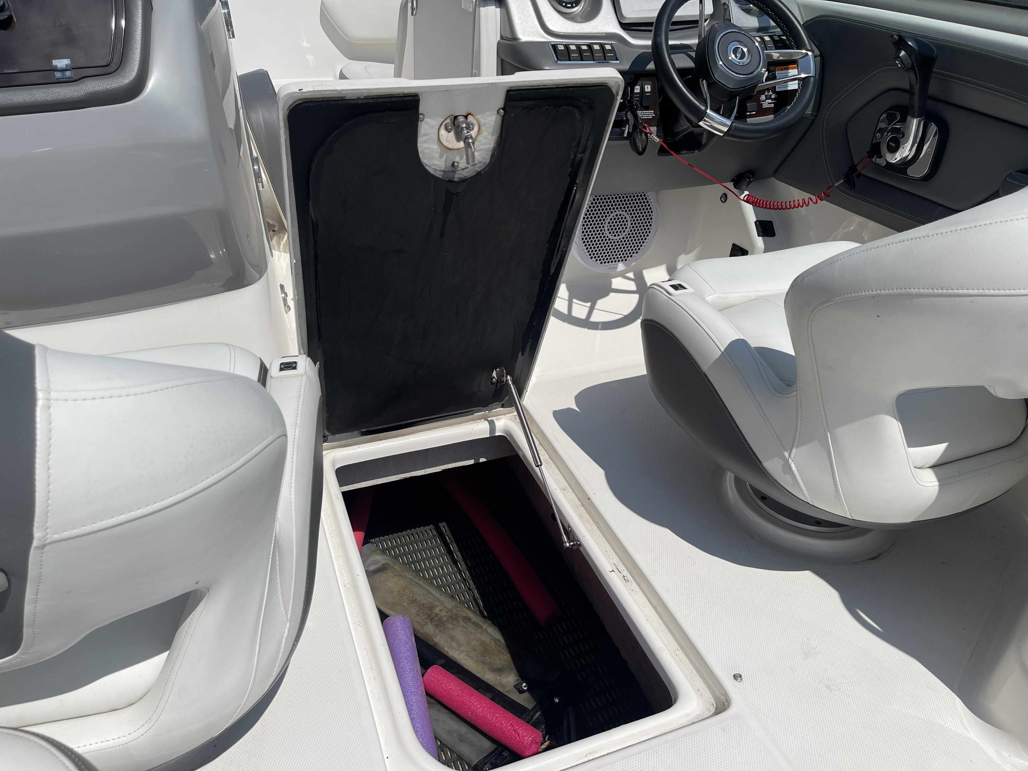 2014 Chaparral Sunesta 224 boat interior with open storage compartment and steering wheel.