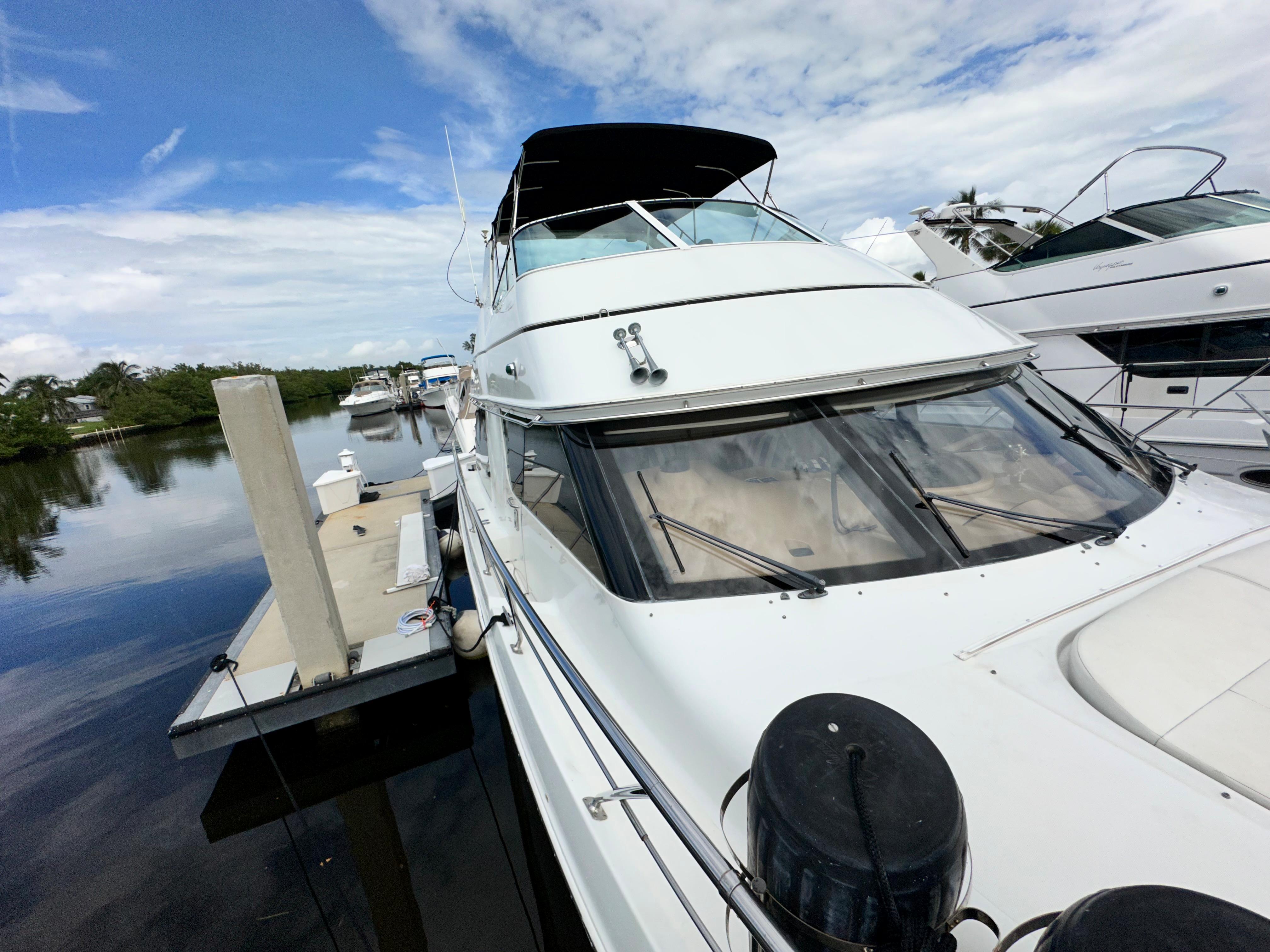 1999 Carver 450 Pilothouse yacht docked at marina under blue sky.