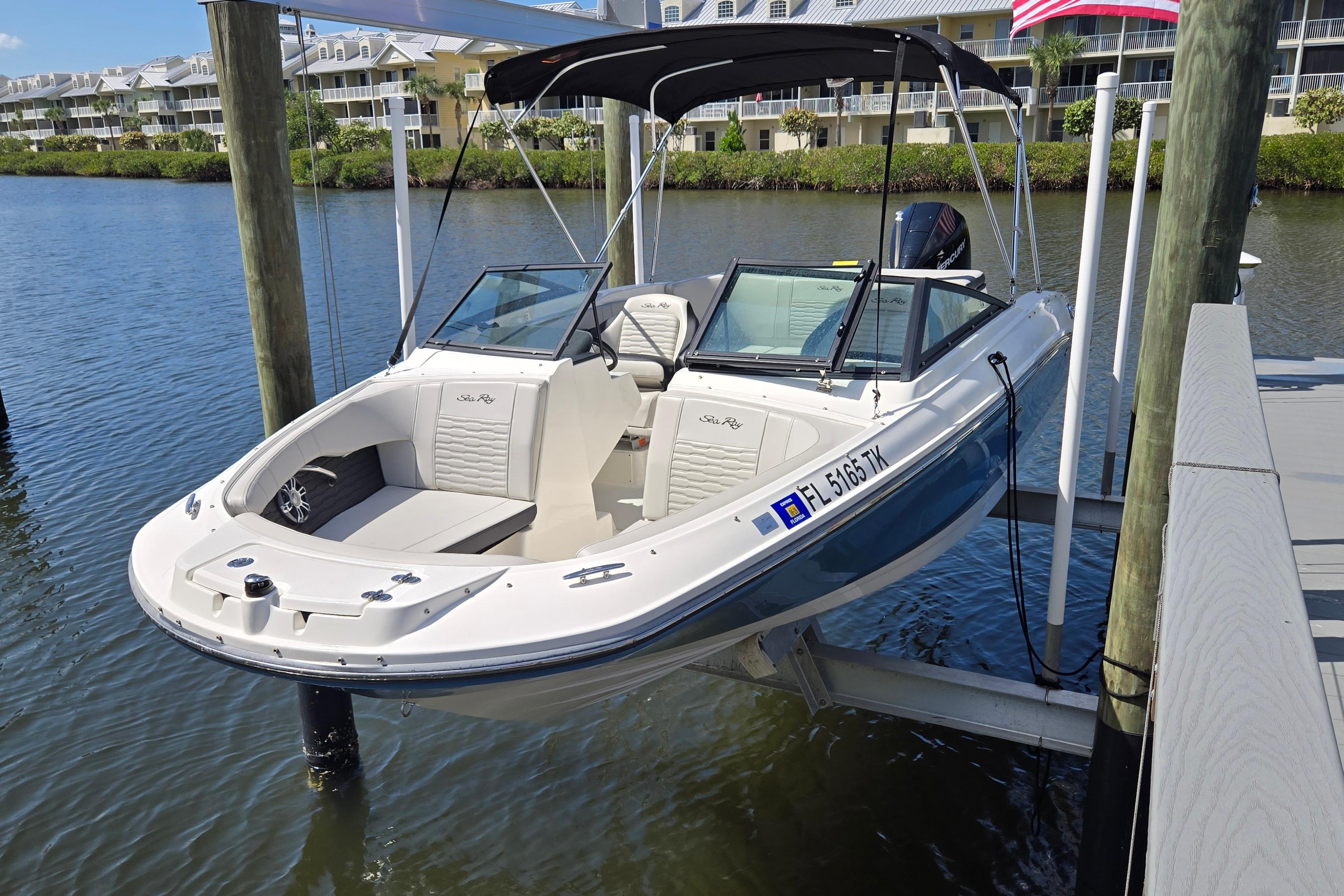 2023 Sea Ray SPX 210 boat docked on a lift by waterfront homes.