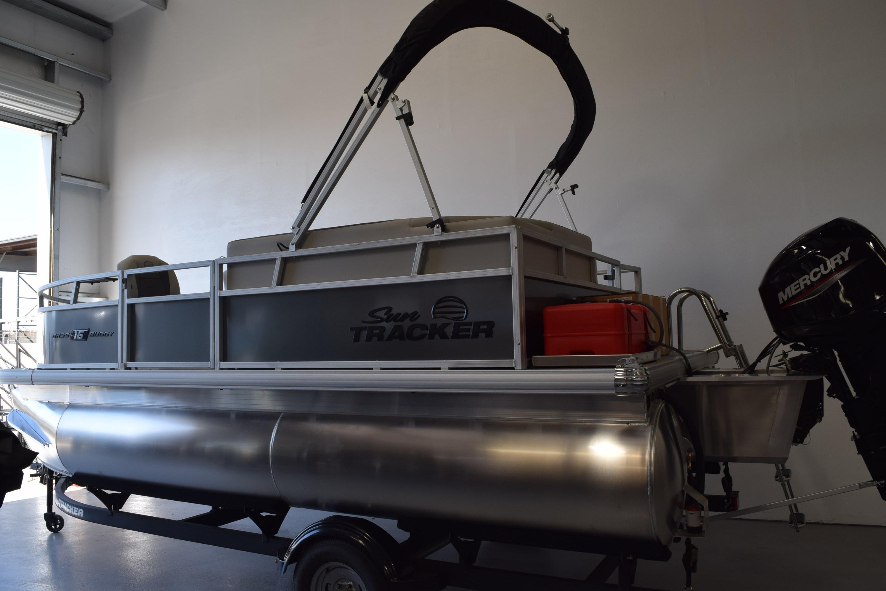 2026 Sun Tracker Bass Buggy 16 XL Select pontoon boat in a garage setting.