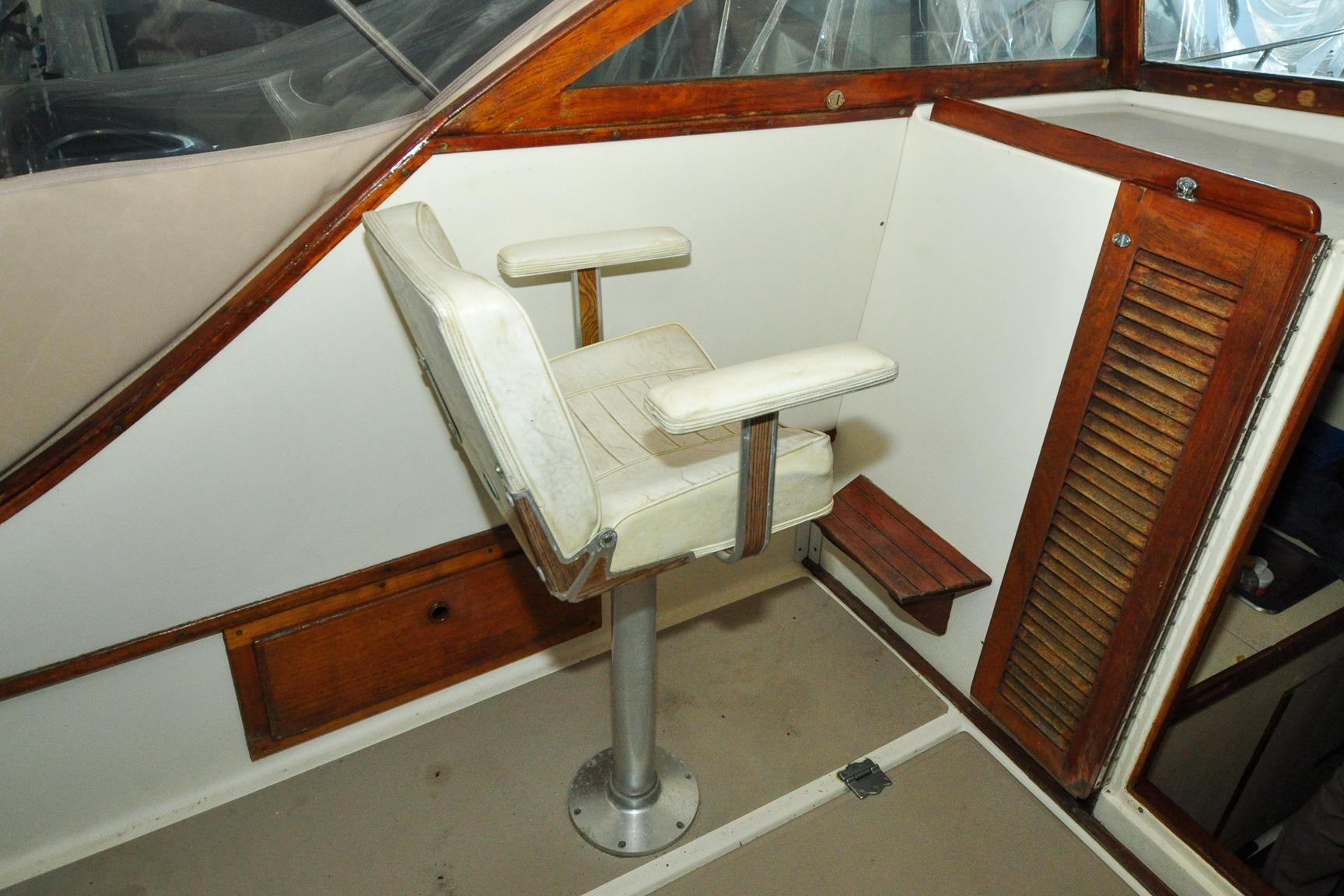 Captain's chair on 1987 Nauset Coastal 27 boat, featuring wood accents and white upholstery.