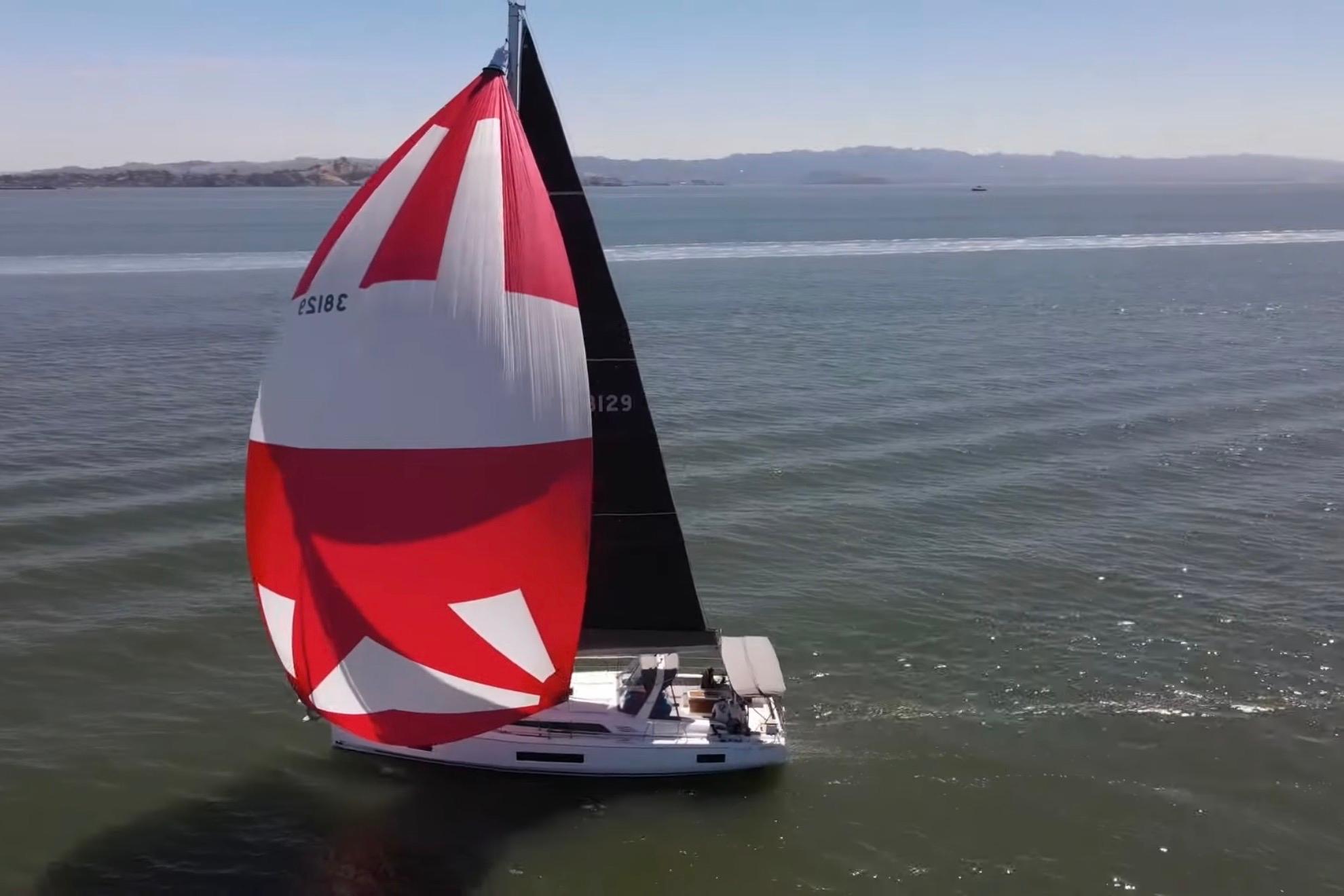 2020 Beneteau Oceanis 46.1 sailing with vibrant red and white spinnaker on open water.