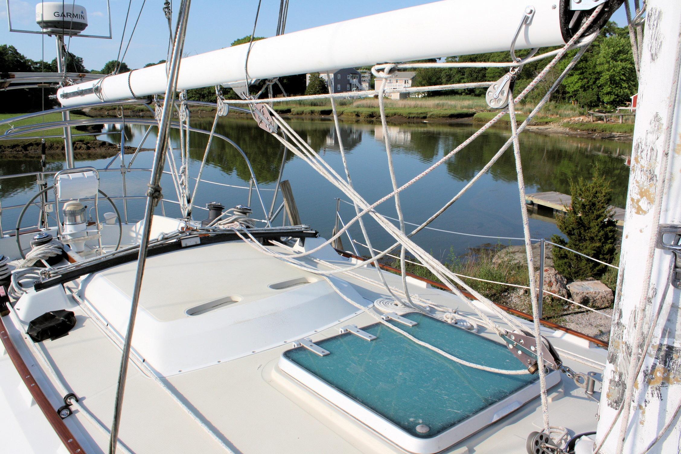 1987 Ericson 38-200 sailboat deck with rigging, docked by a serene river.