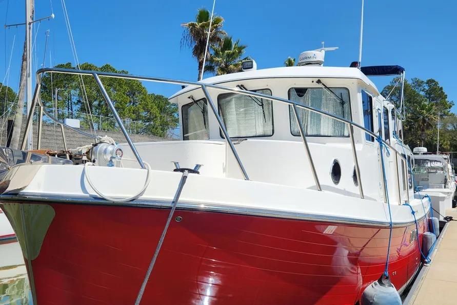 2006 American Tug AT boat with red hull docked under clear blue sky.