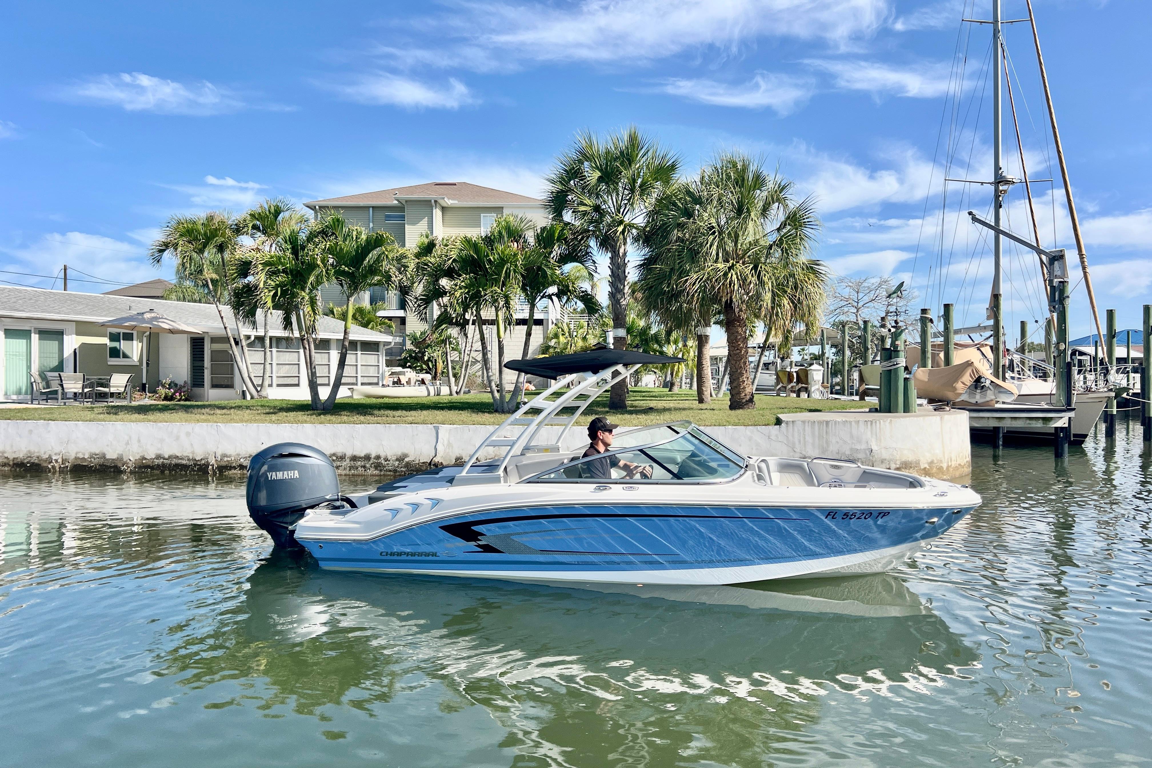 2023 Chaparral 21 SSi OB boat cruising near palm trees and waterfront homes.