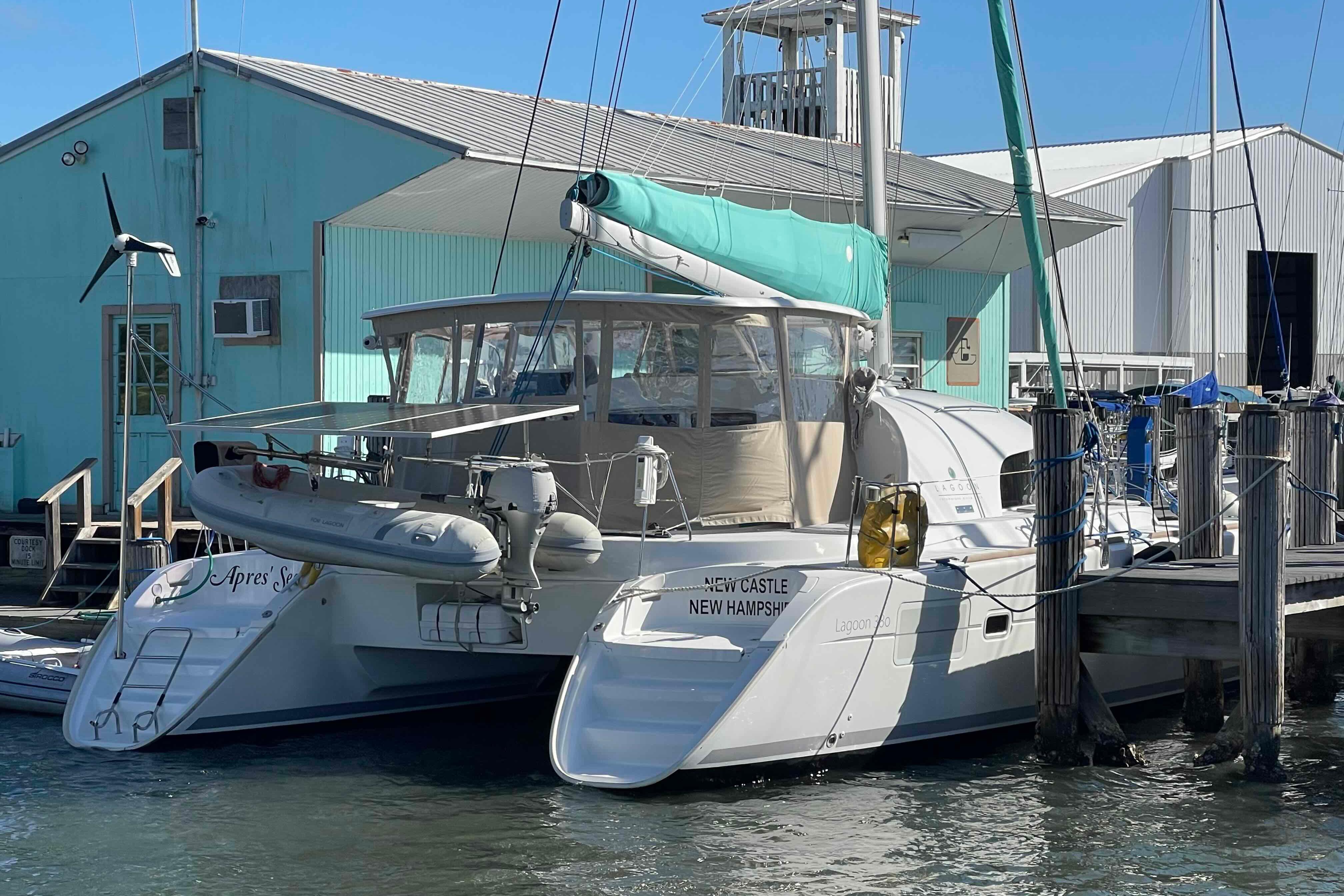 2012 Lagoon 380 S2 catamaran docked at marina, turquoise building in background.