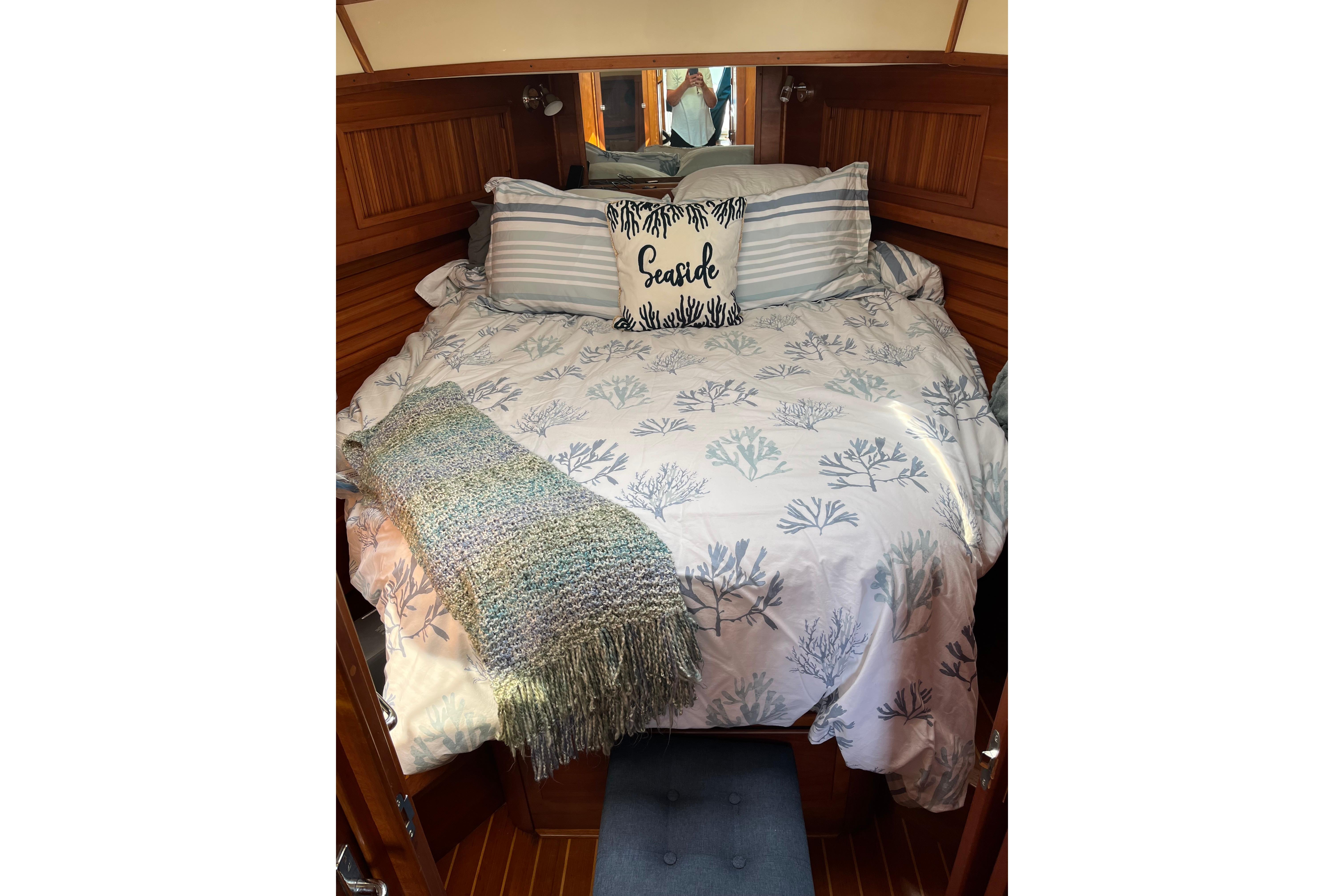 Cozy cabin interior of 2005 Sea Ray 300 Sundancer with nautical-themed bedding.
