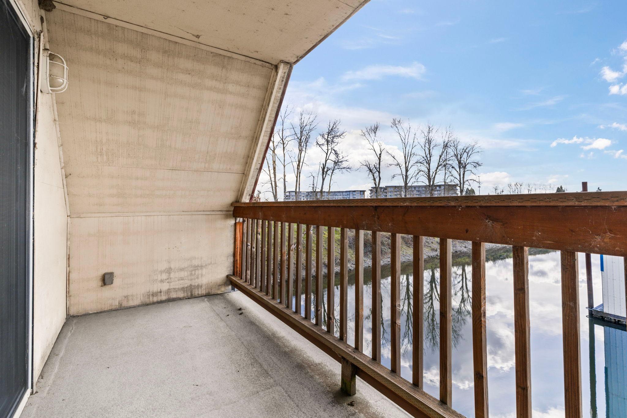 Balcony view from a 1976 custom boathouse overlooking a serene waterway and trees.