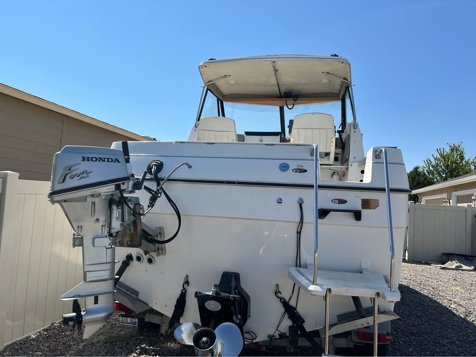 Rear view of a 1999 Bayliner 2452 boat with Honda outboard motor.