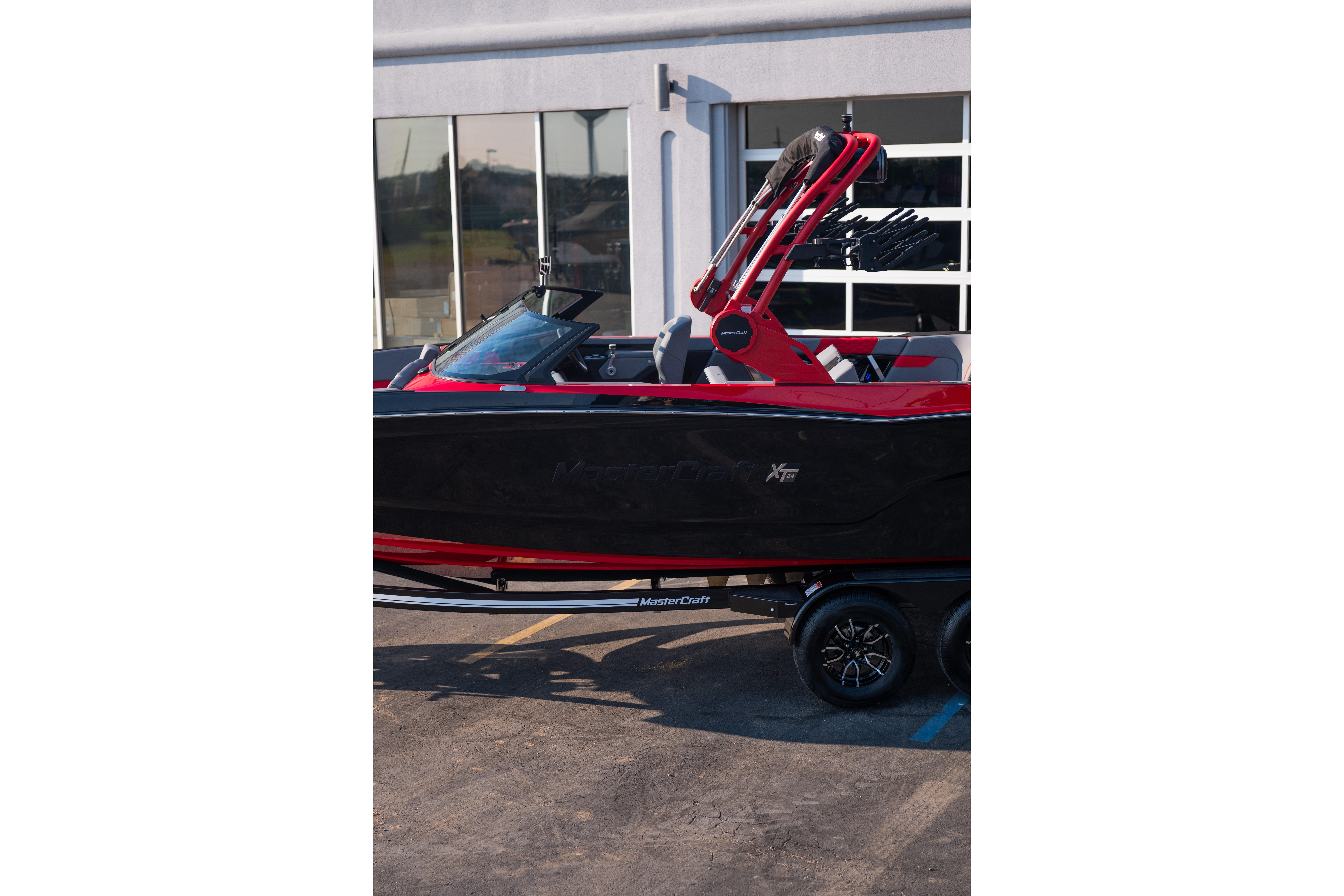 2027 MasterCraft XT24 boat in black and red, parked on a trailer.