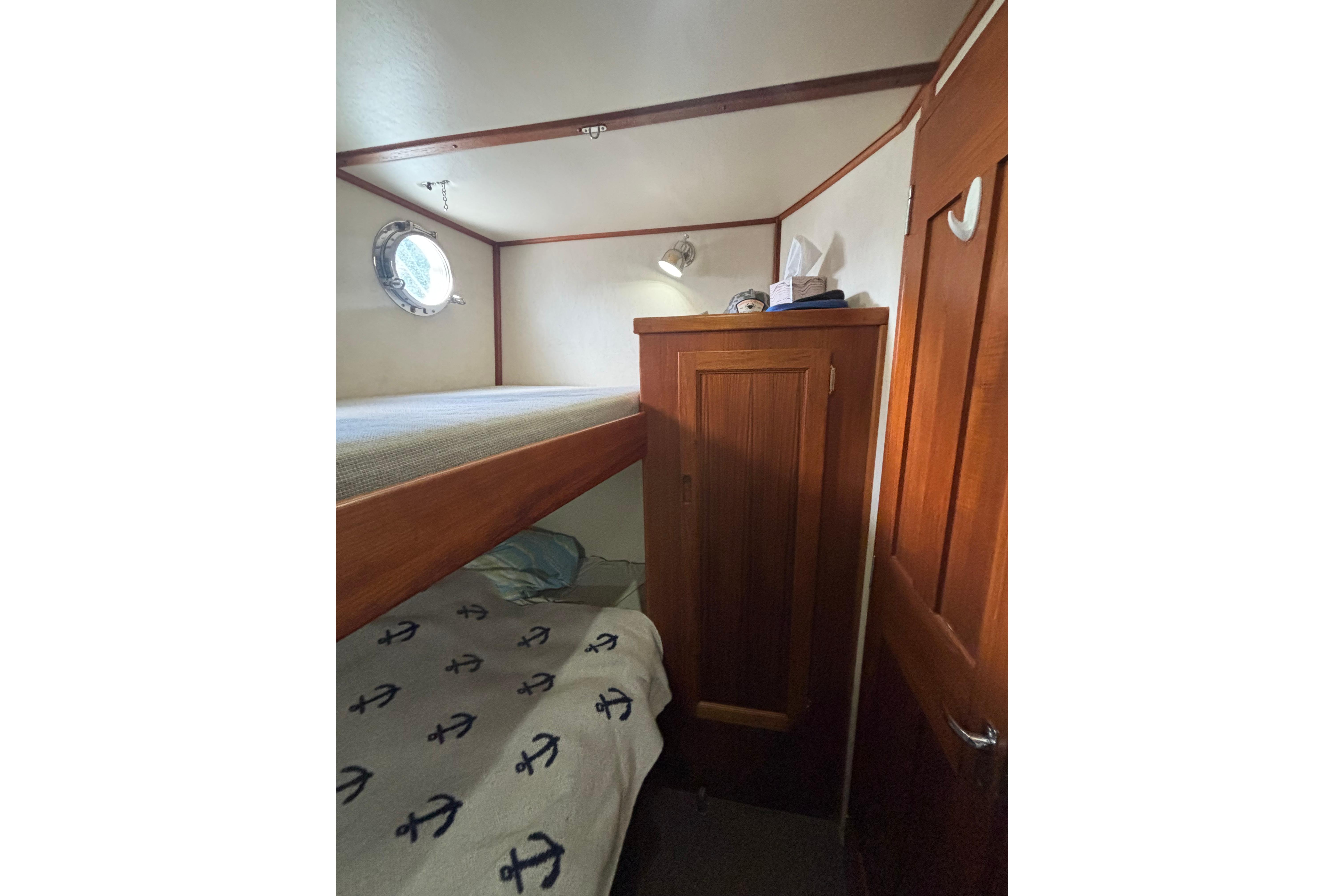 Cozy cabin interior of 2004 Nordic Tug 37 with bunk beds and wooden cabinetry.