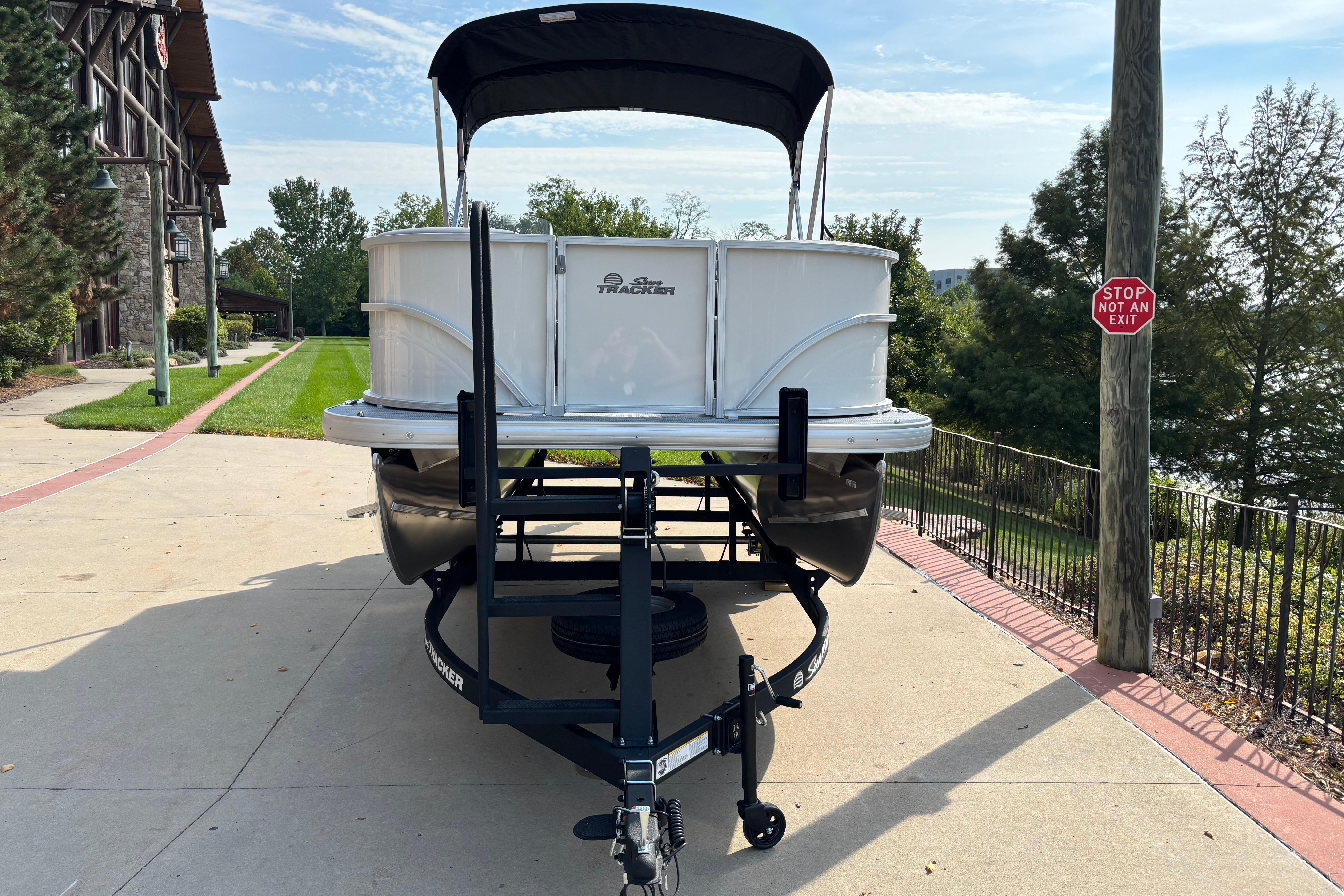 2026 Sun Tracker Party Barge 16 DLX on trailer, parked near a scenic pathway.