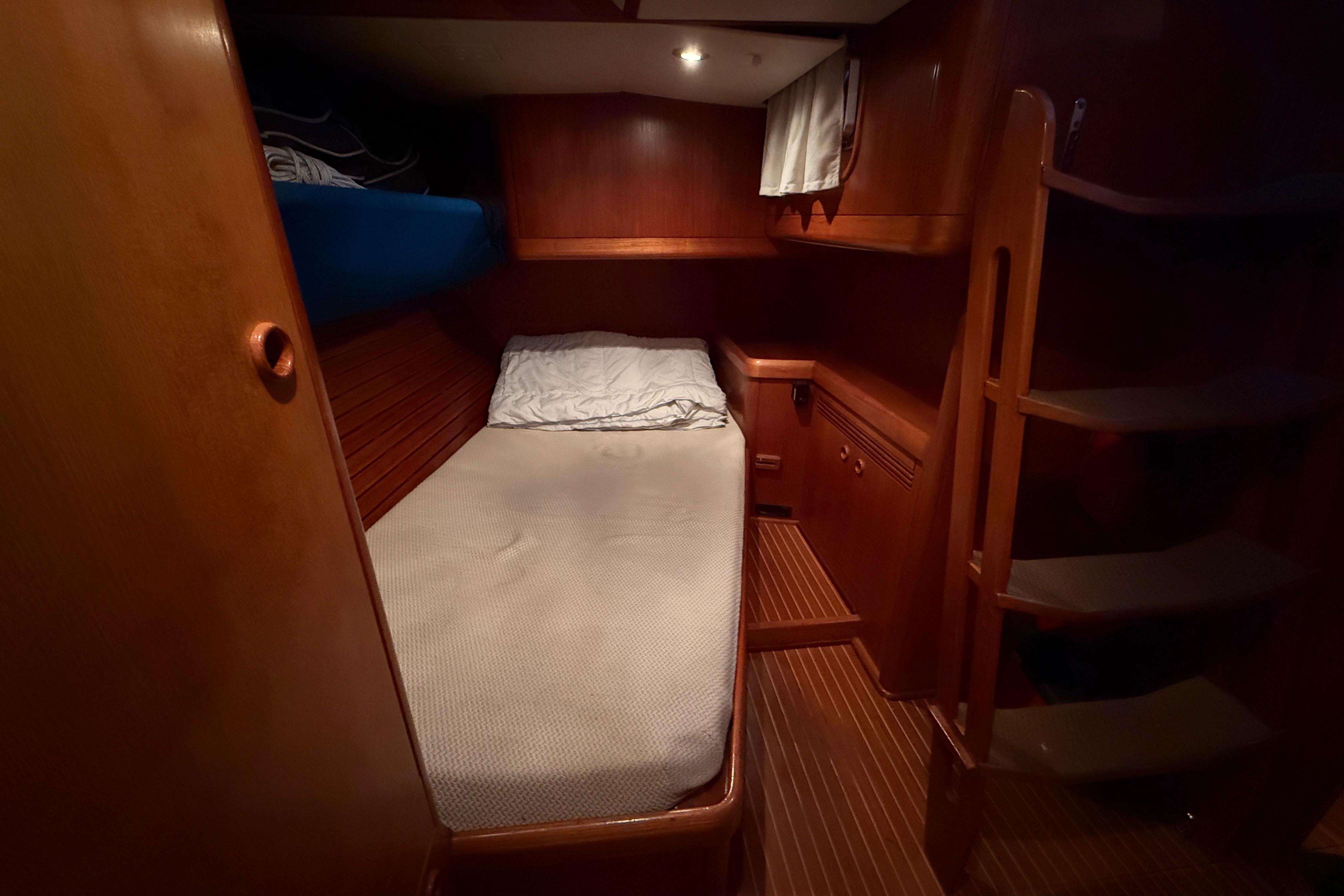 Cozy cabin interior of 1997 Nautor Swan 56R yacht with wooden finish and bedding.