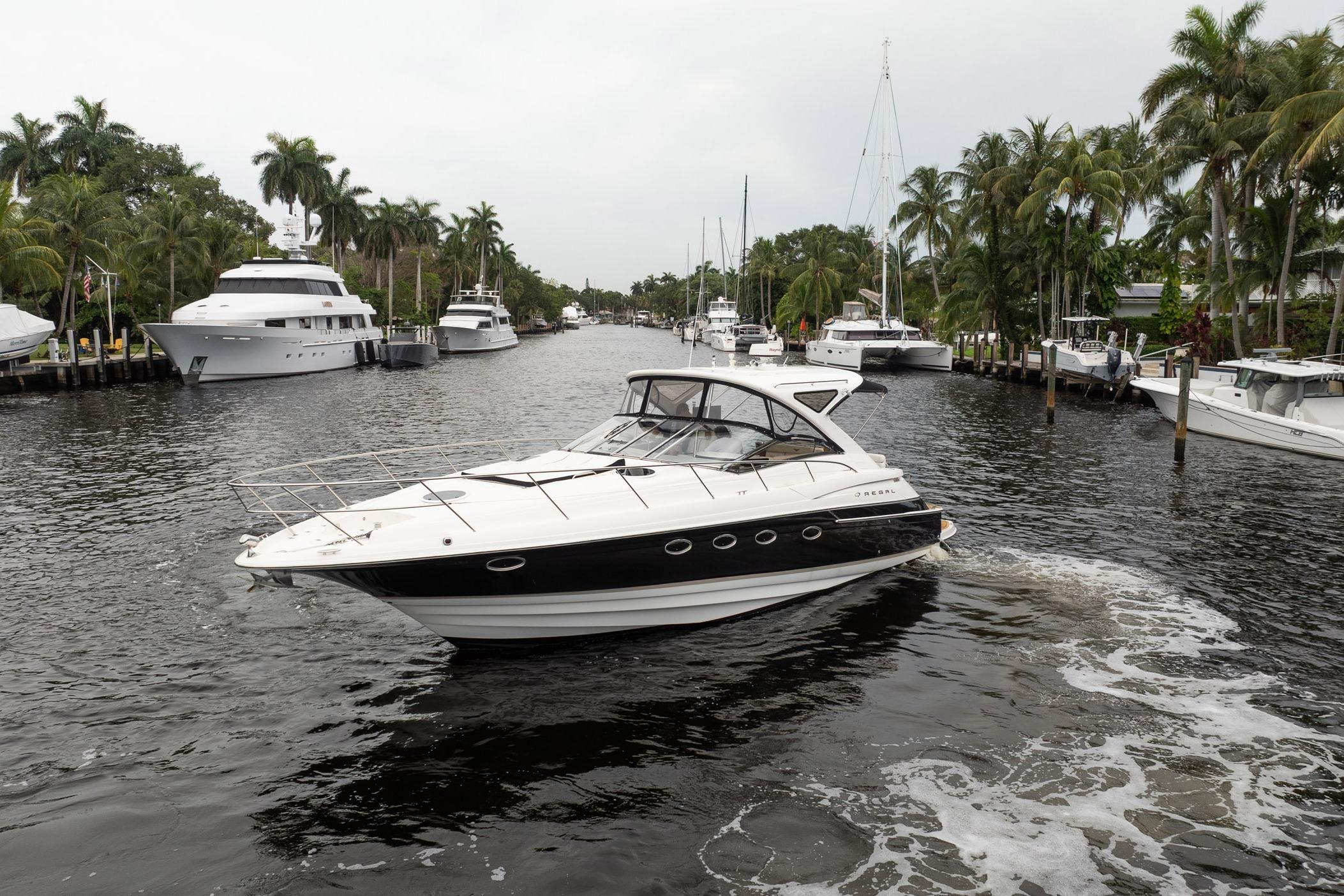 2008 Regal Commodore 4460 yacht cruising in a scenic, palm-lined waterway.