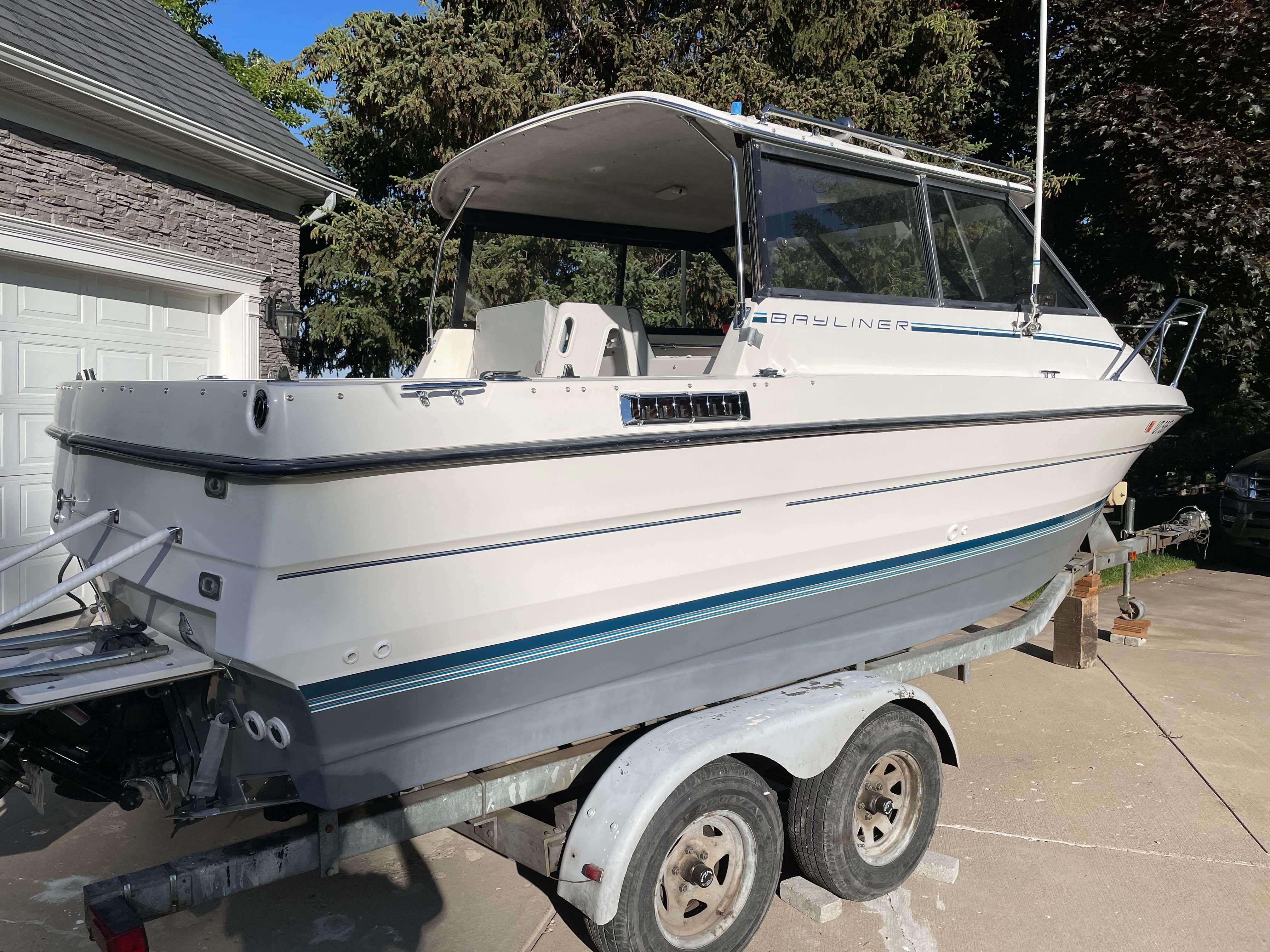 A 1991 Bayliner 2159 boat on a trailer in a driveway.