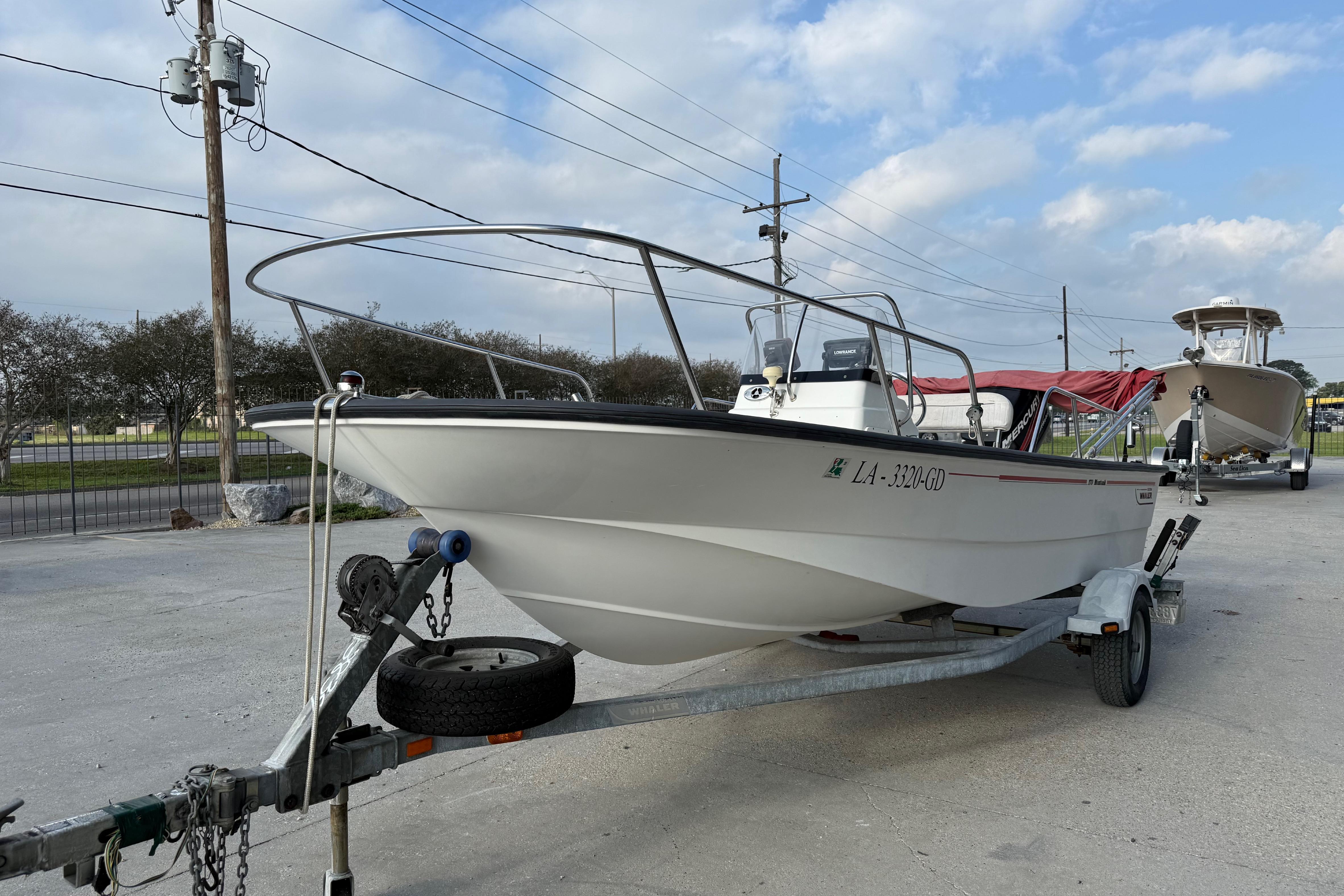 2005 Boston Whaler 17 Montauk boat on trailer, parked outdoors under cloudy sky.