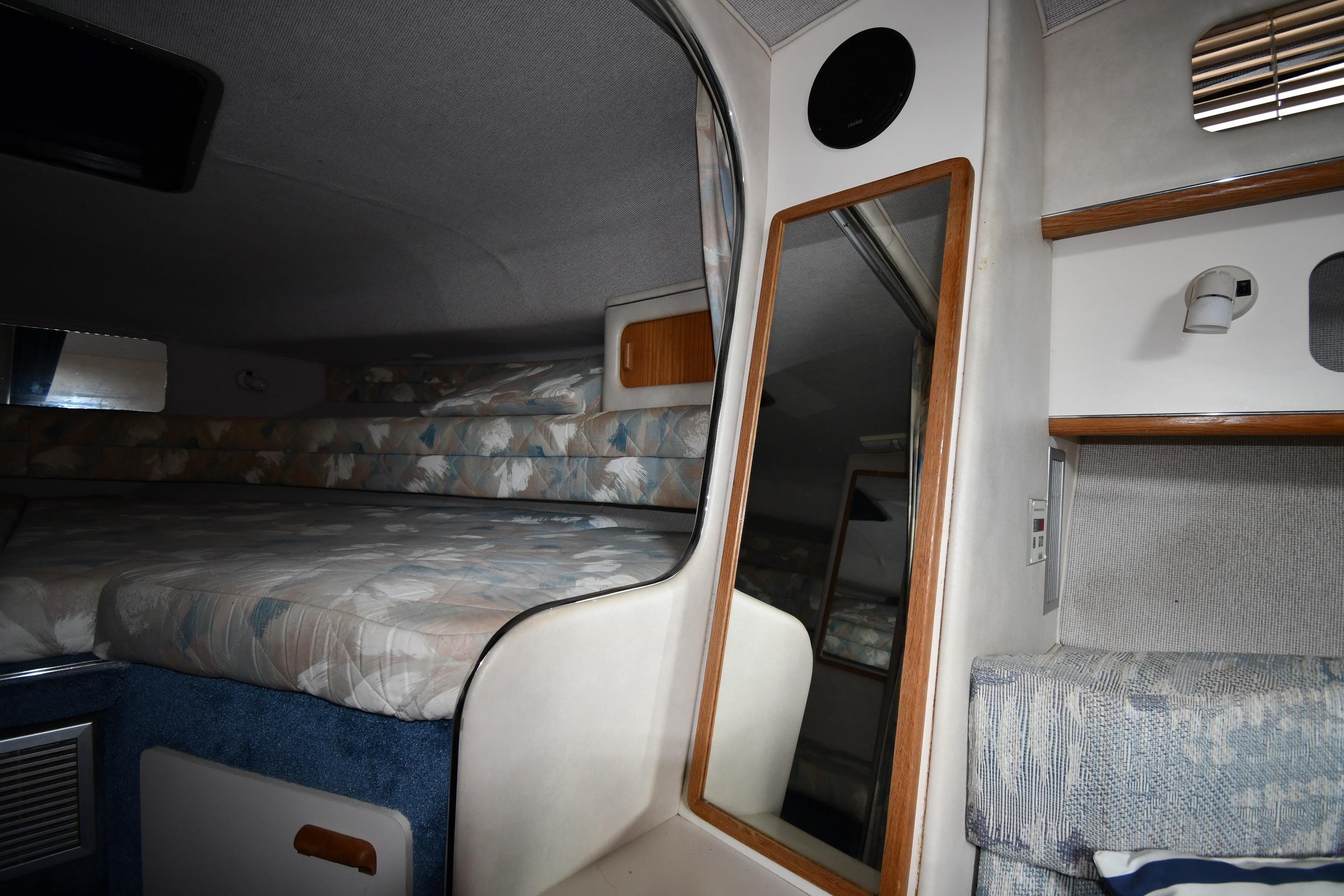 Interior cabin of 1993 Sea Ray 300 Sundancer with bed, mirror, and storage shelves.