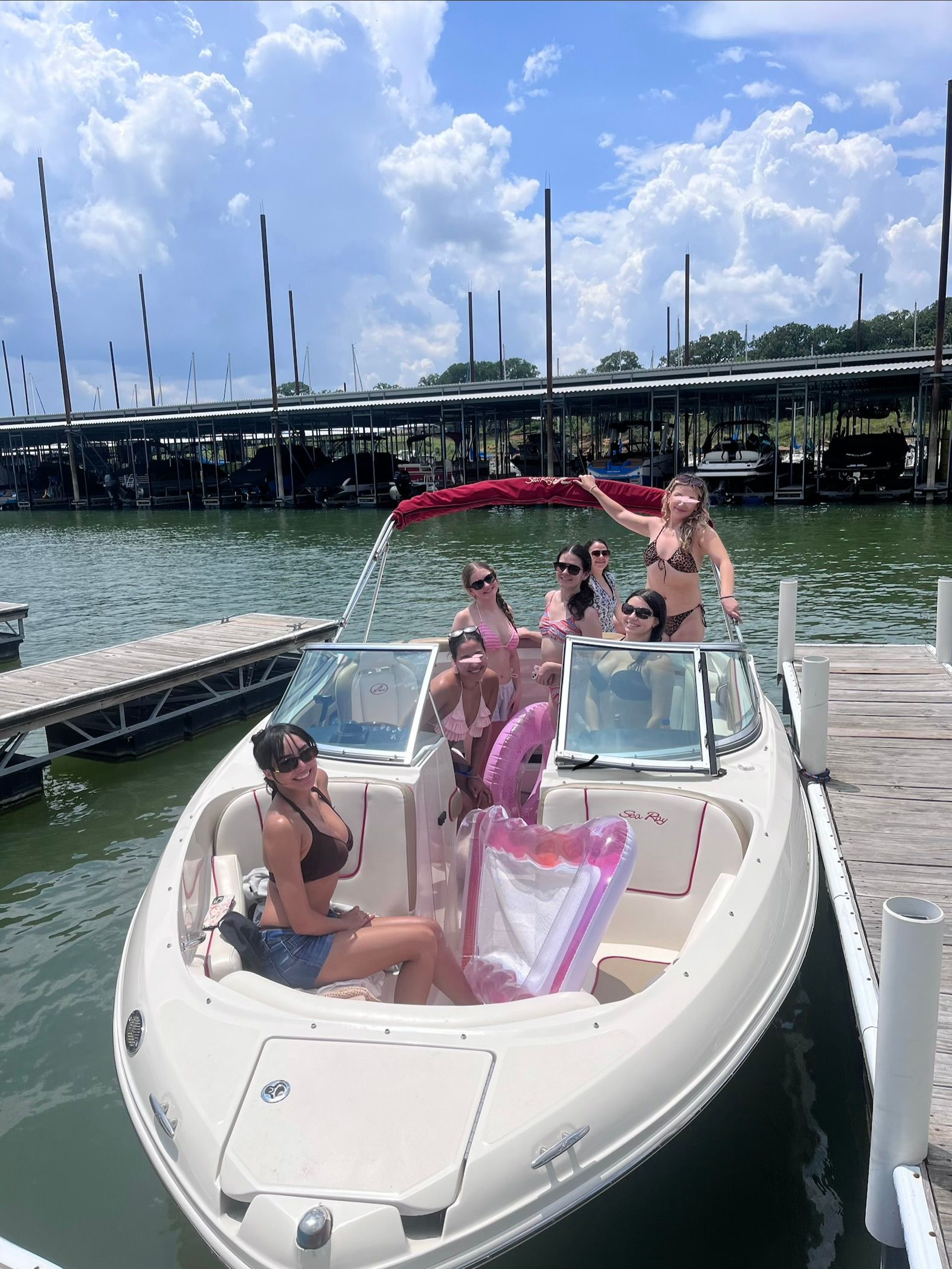A group of people sitting on a Sea Ray 210 Select boat at the dock.