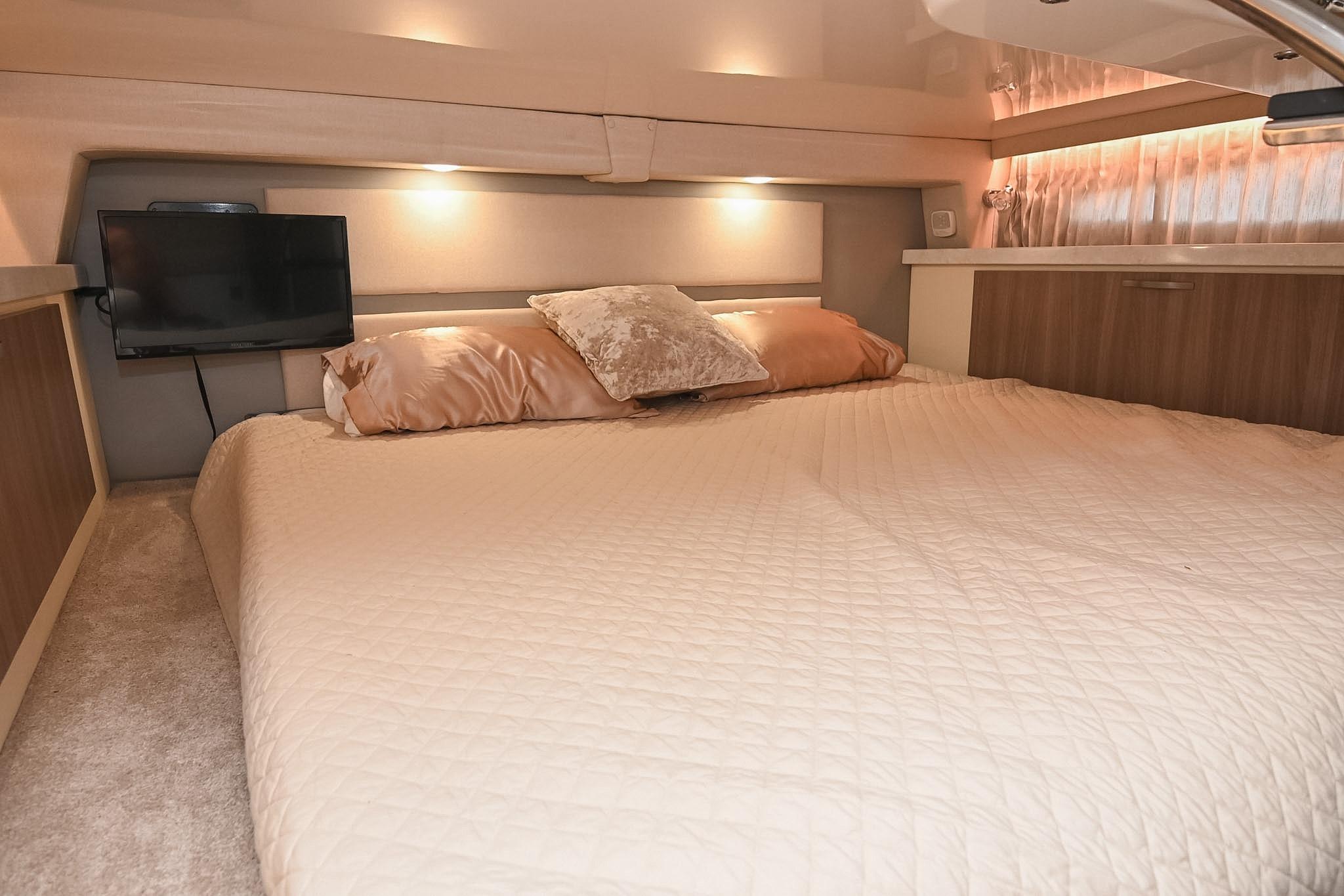Luxurious cabin interior of 2021 Regal 33 Express yacht with cozy bedding and ambient lighting.