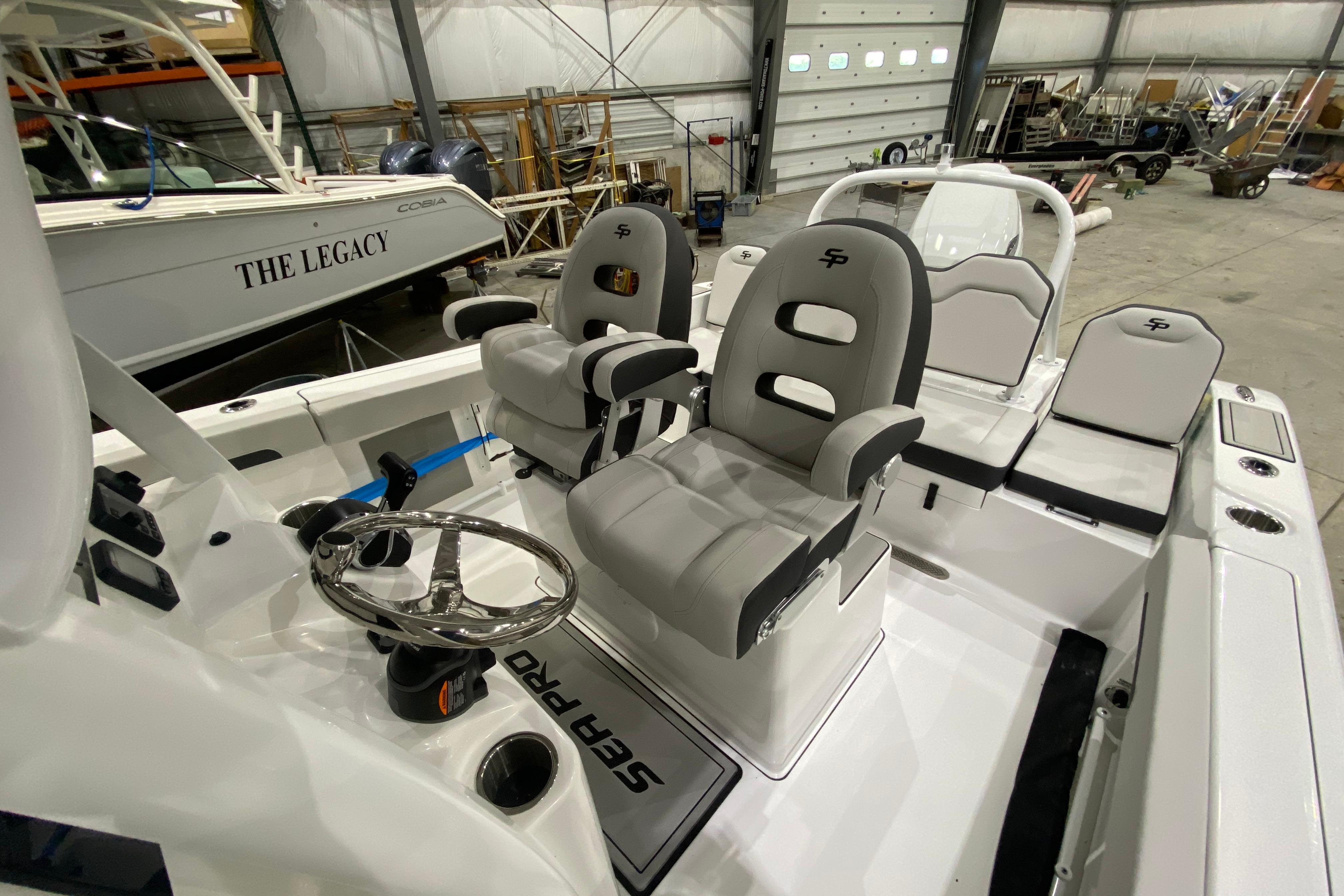 2027 Sea Pro 245FLXR Sandbar boat interior with dual captain chairs in a spacious garage.