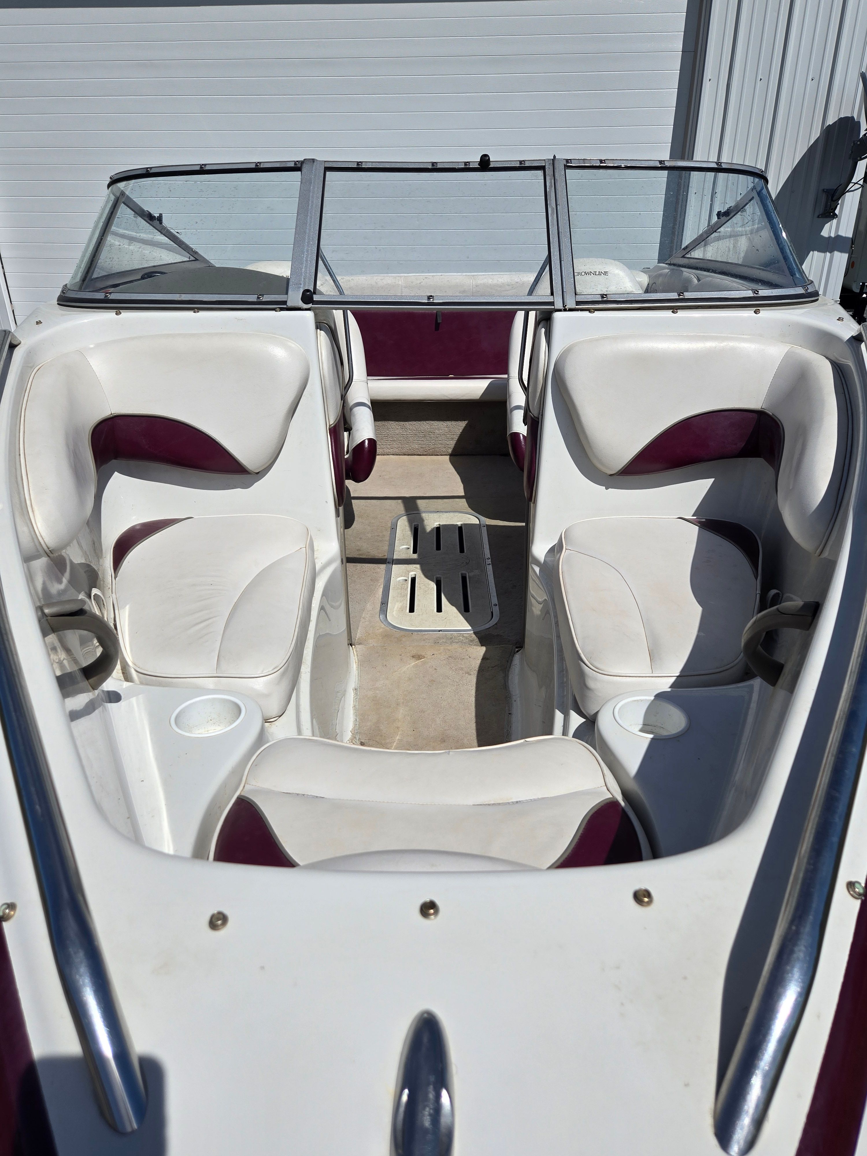The image shows the cockpit of a 2001 Crownline 180 BR boat with white and maroon seats.