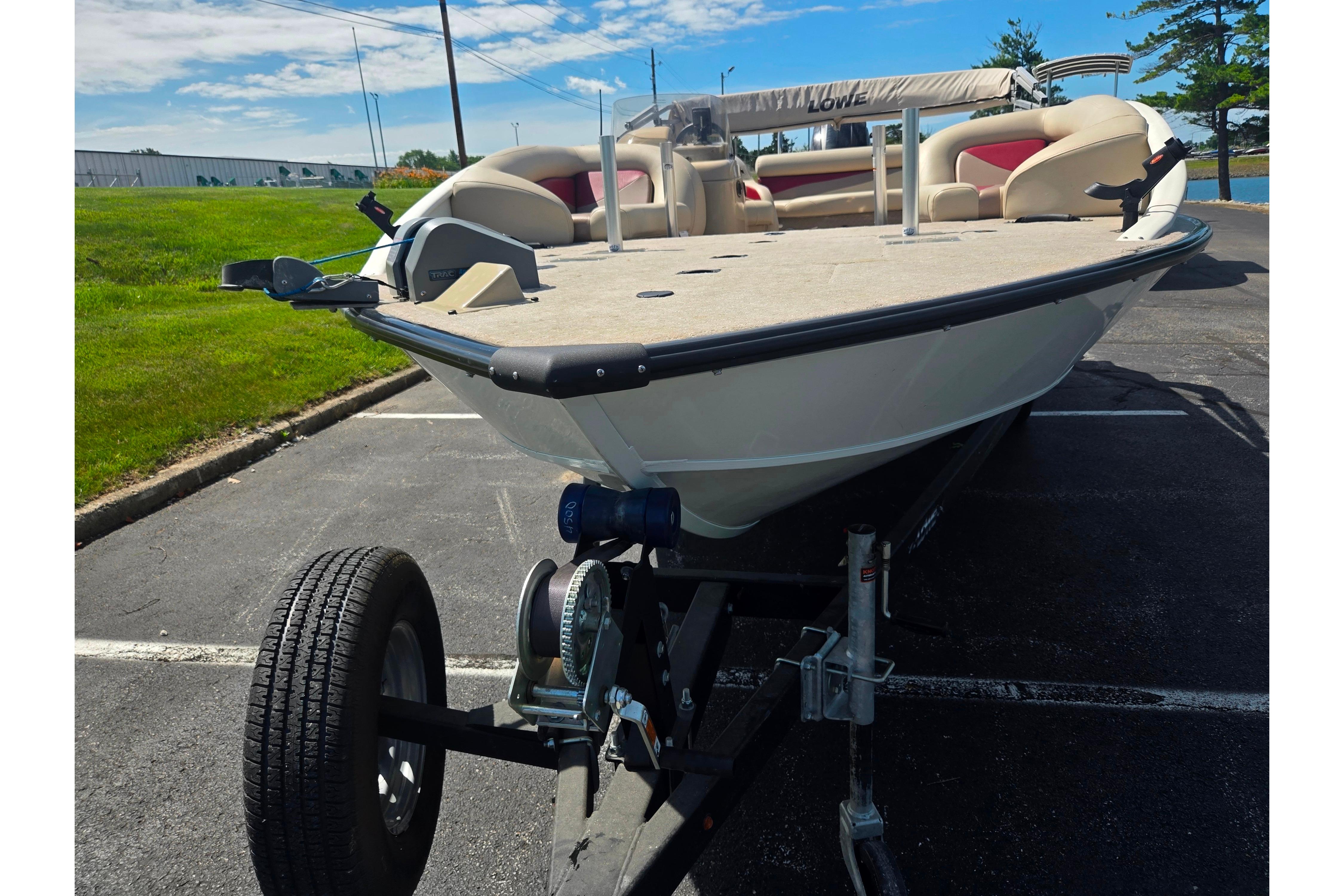2015 Lowe Sport Deck 224 boat on trailer in parking lot, sunny day.