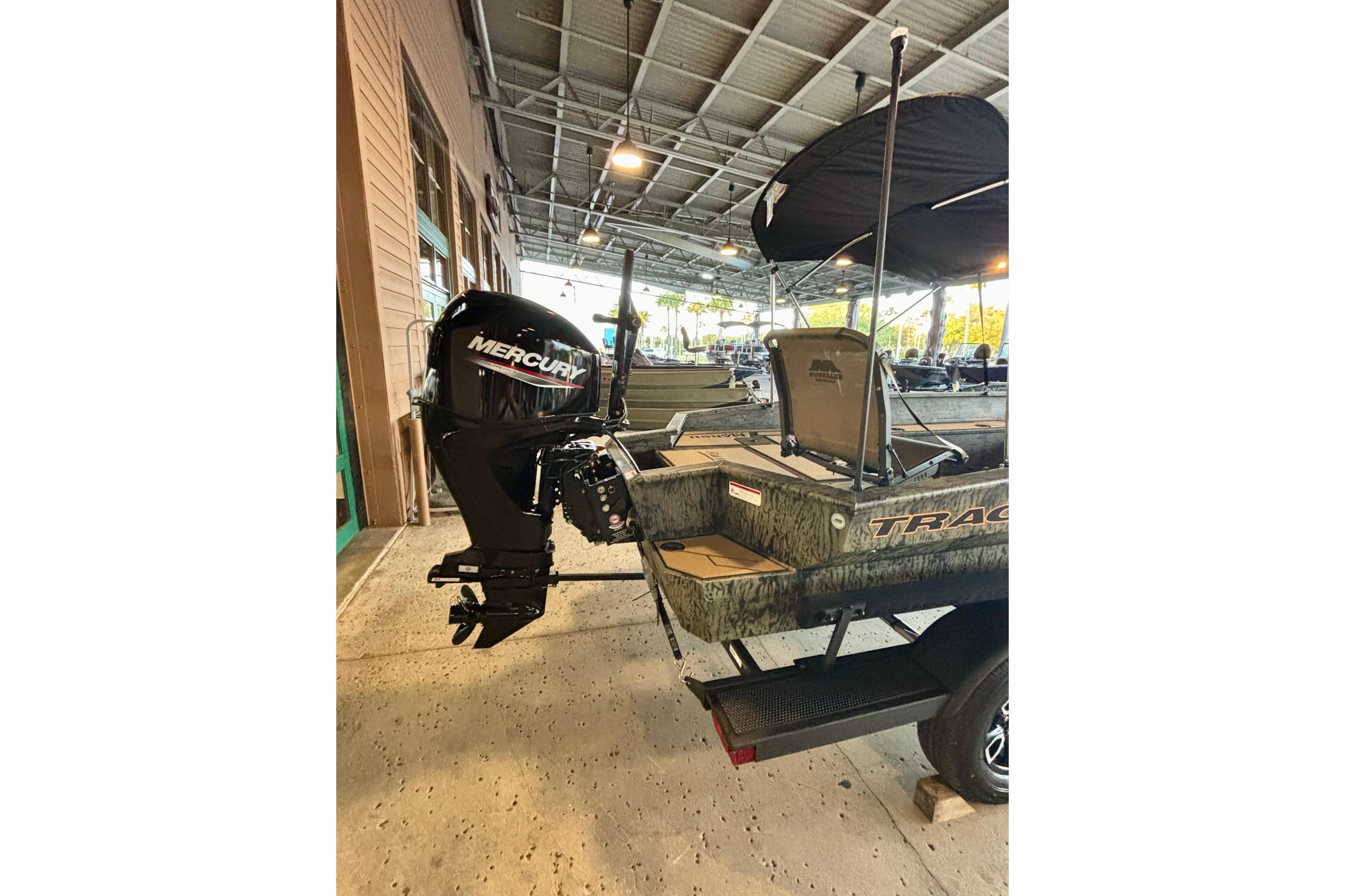 2026 Tracker Grizzly 1756 T Marsh boat with Mercury outboard motor in covered storage.