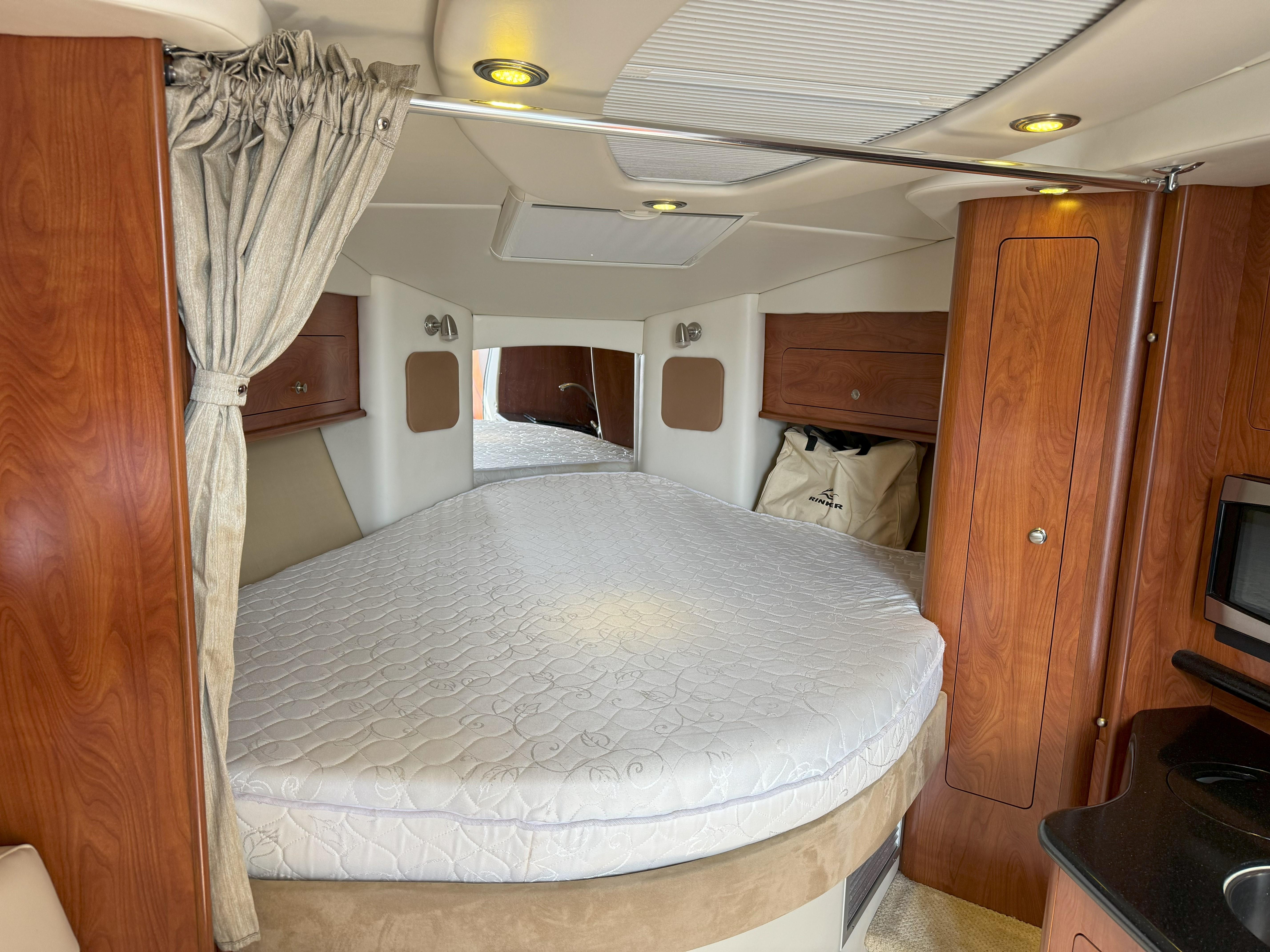 Interior of a 2010 Rinker 310 Express Cruiser with bed and wood paneling.