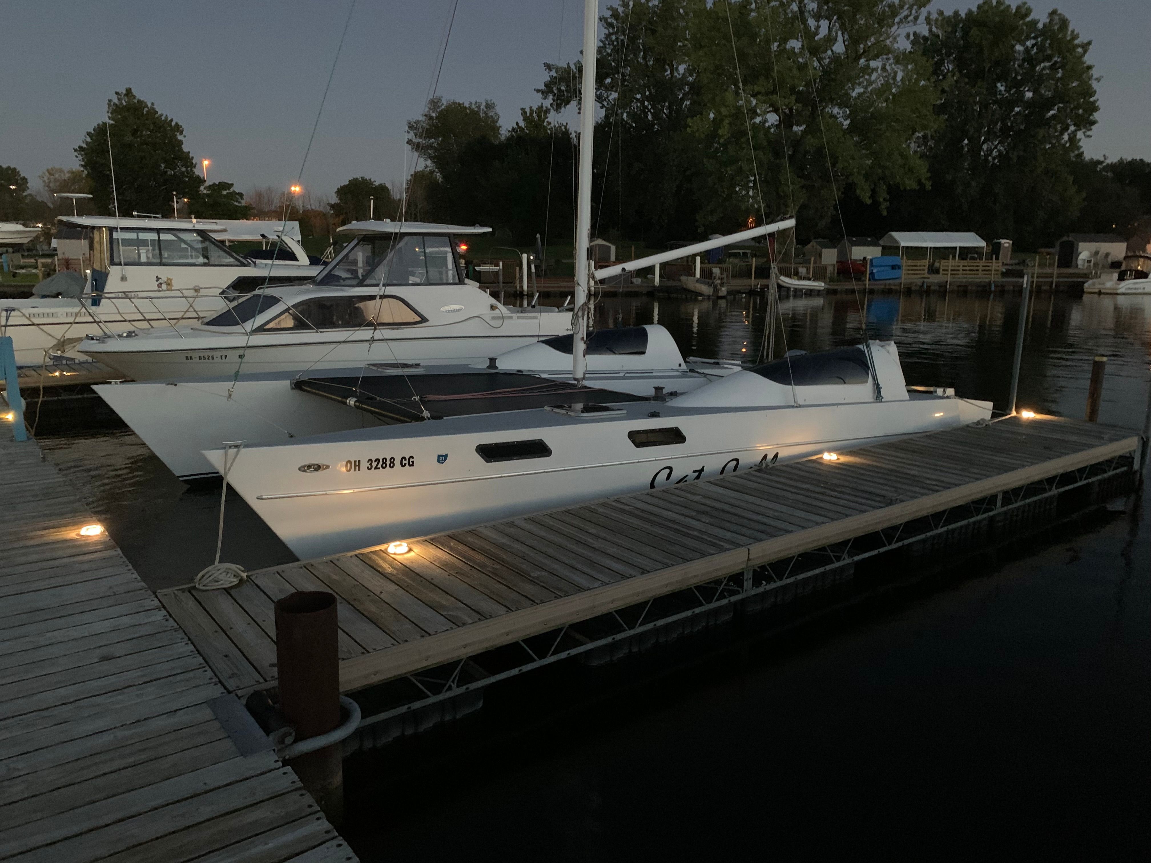 A 1981 Catamaran Cat Calls docked at a lit pier in a calm harbor.