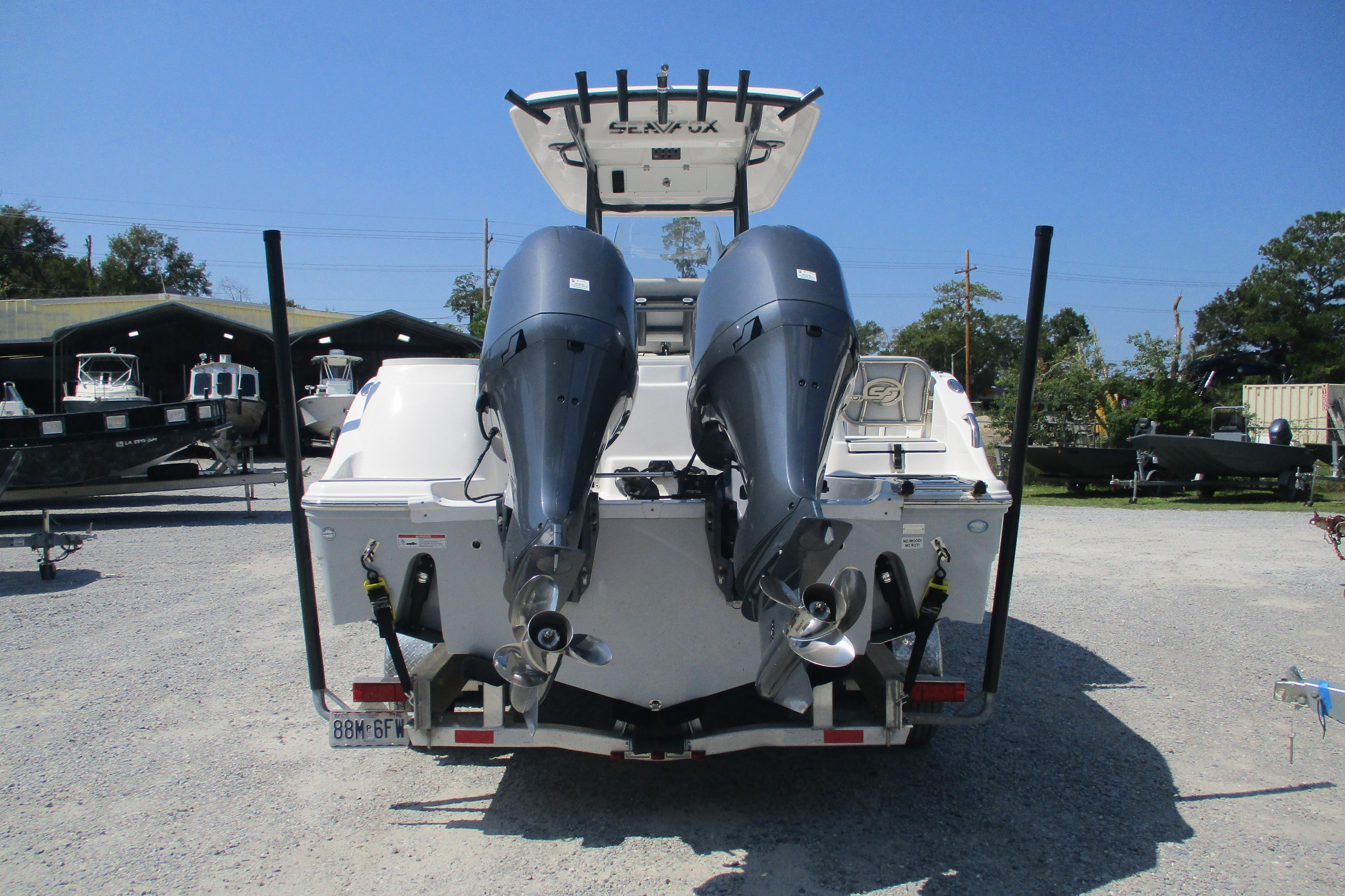 2024 Sea Fox 268 Commander boat with dual outboard motors, parked on gravel lot.