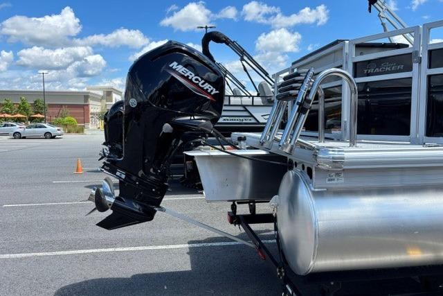 2026 Sun Tracker Fishin' Barge 20 DLX with Mercury outboard motor in parking lot.